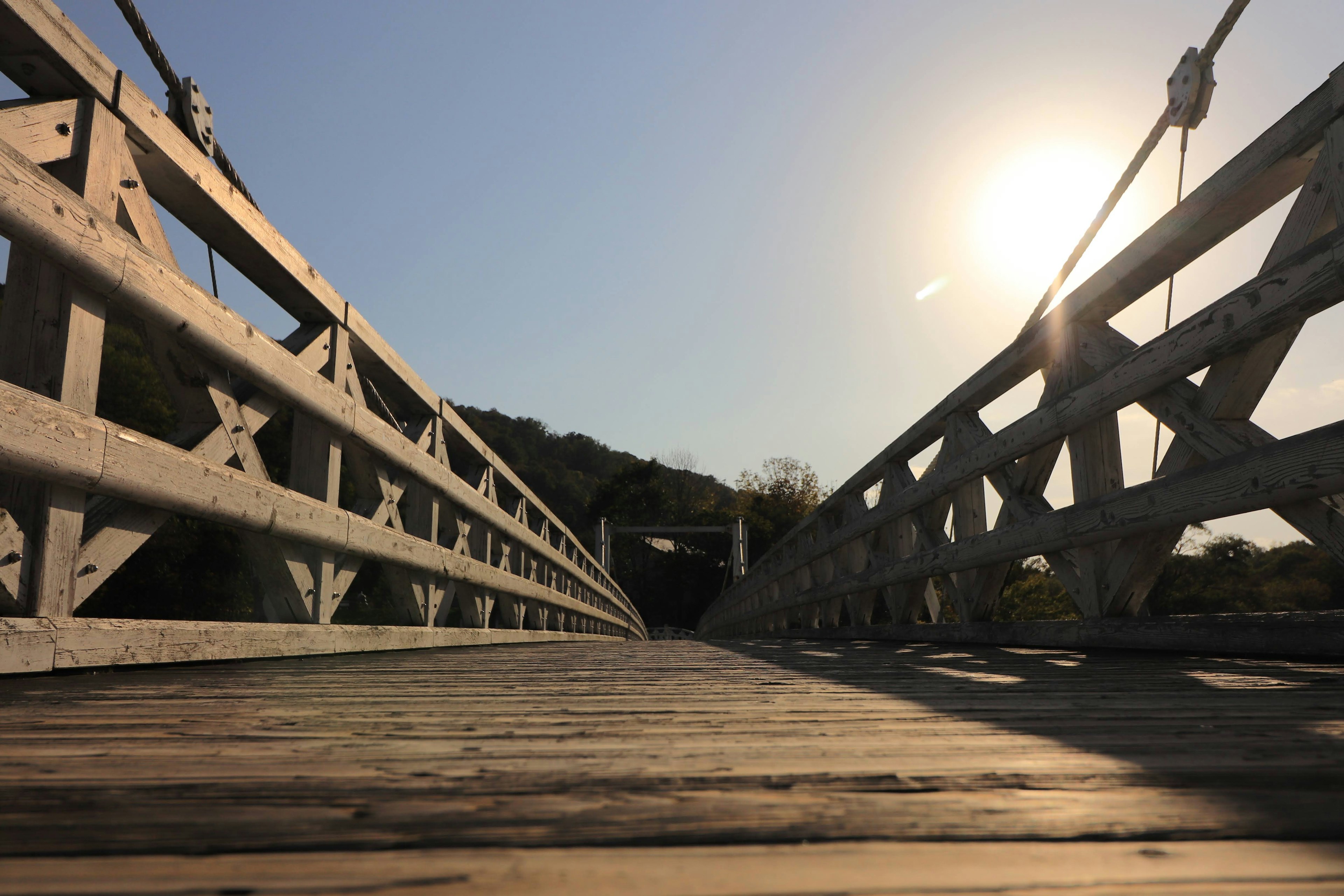 Vista de un puente colgante de madera con luz solar