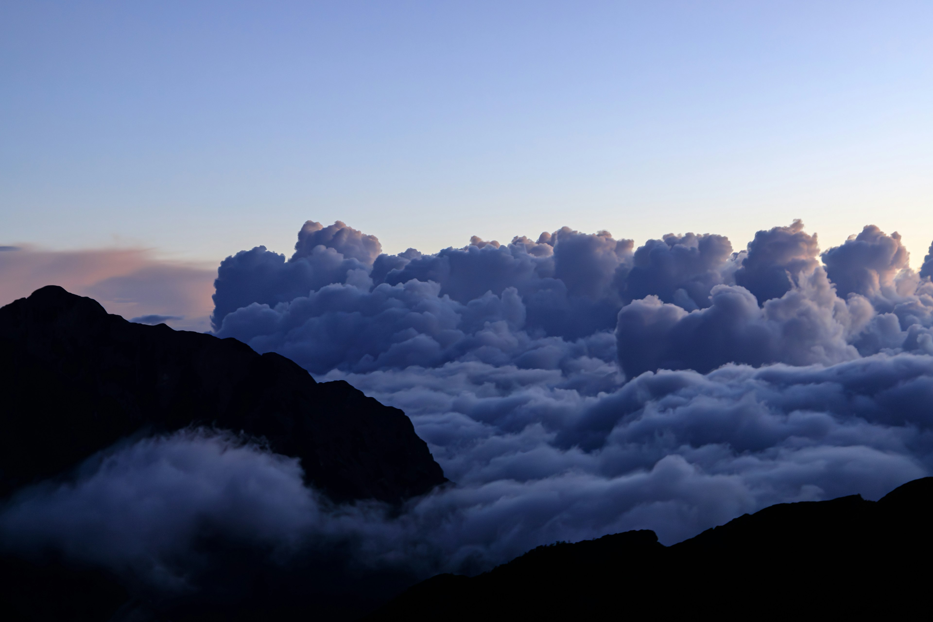 Beau paysage de silhouette de montagne contre une mer de nuages