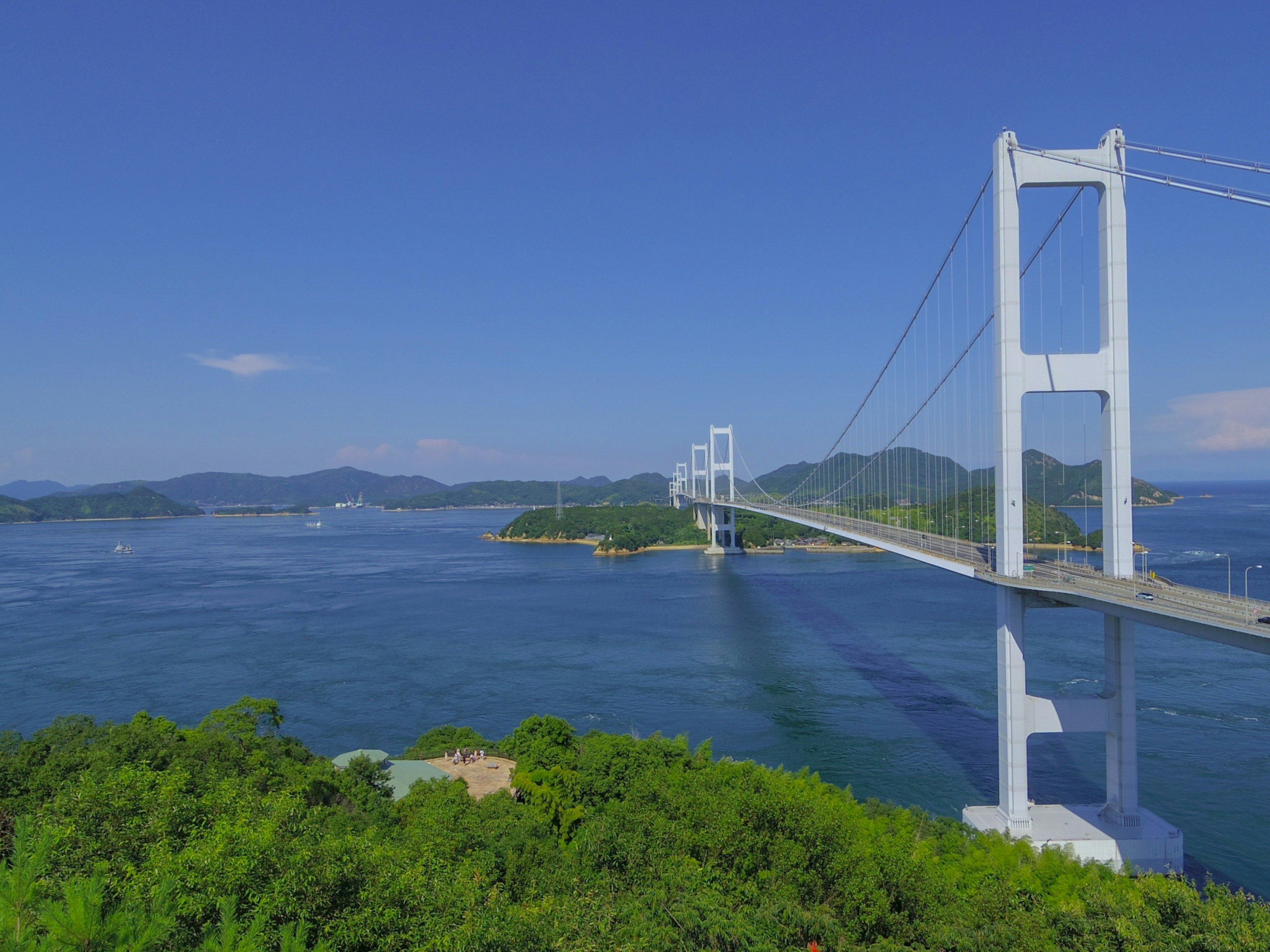 Un hermoso puente que cruza aguas azules bajo un cielo despejado con islas verdes cercanas