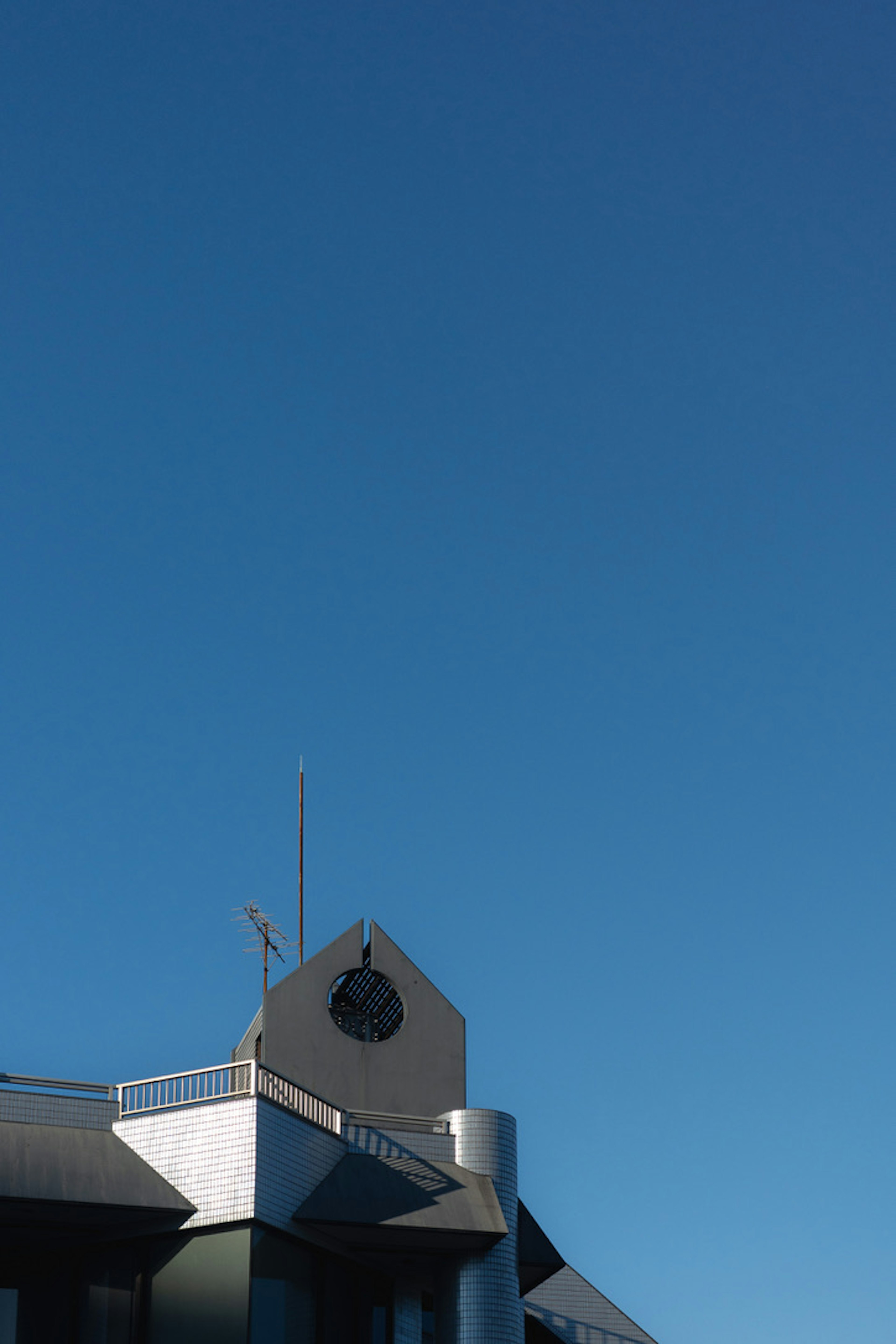 Parte de un edificio moderno bajo un cielo azul con un símbolo visible en el techo