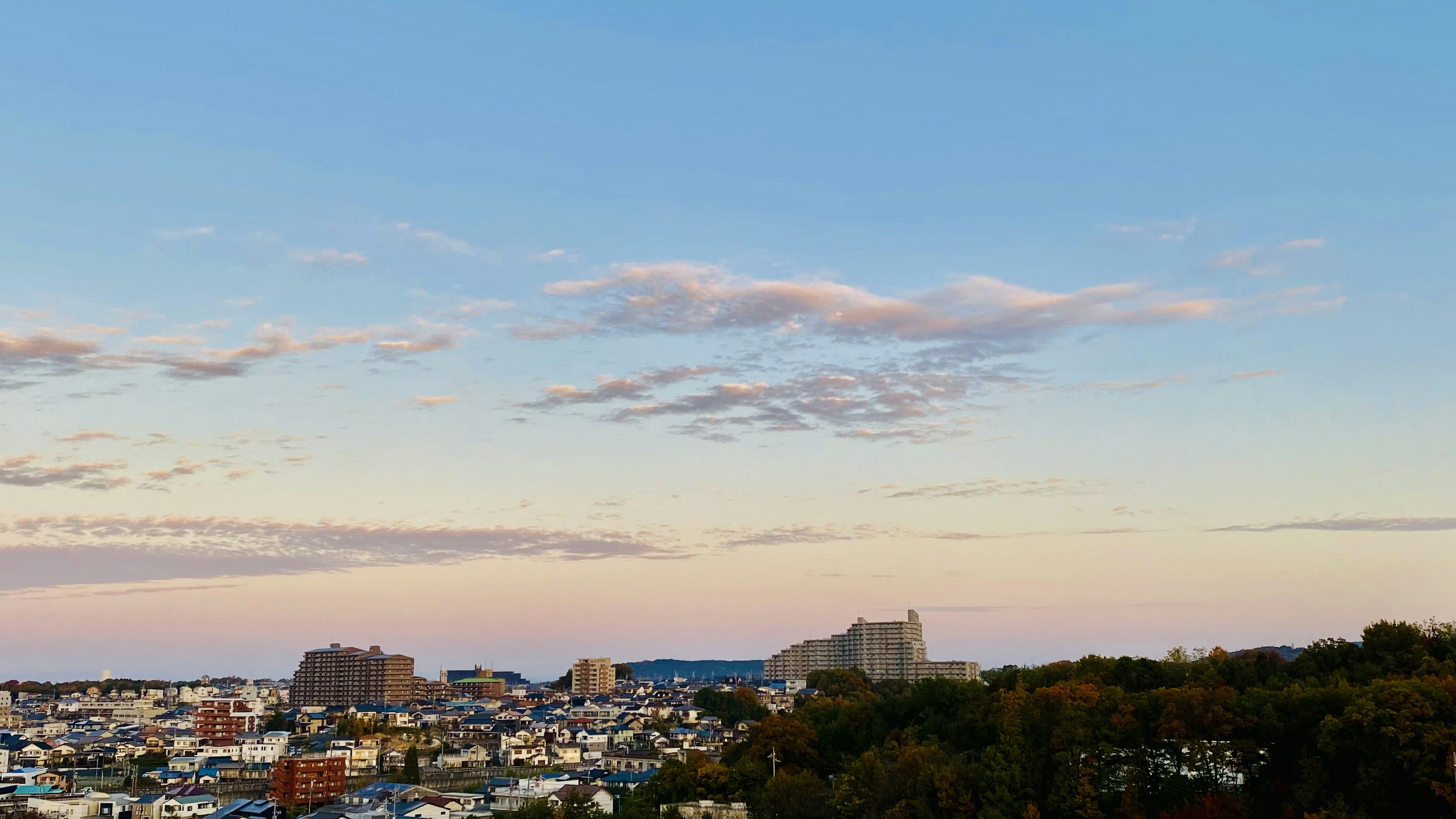 Vista panorámica de una ciudad al atardecer con cielo azul y nubes suaves