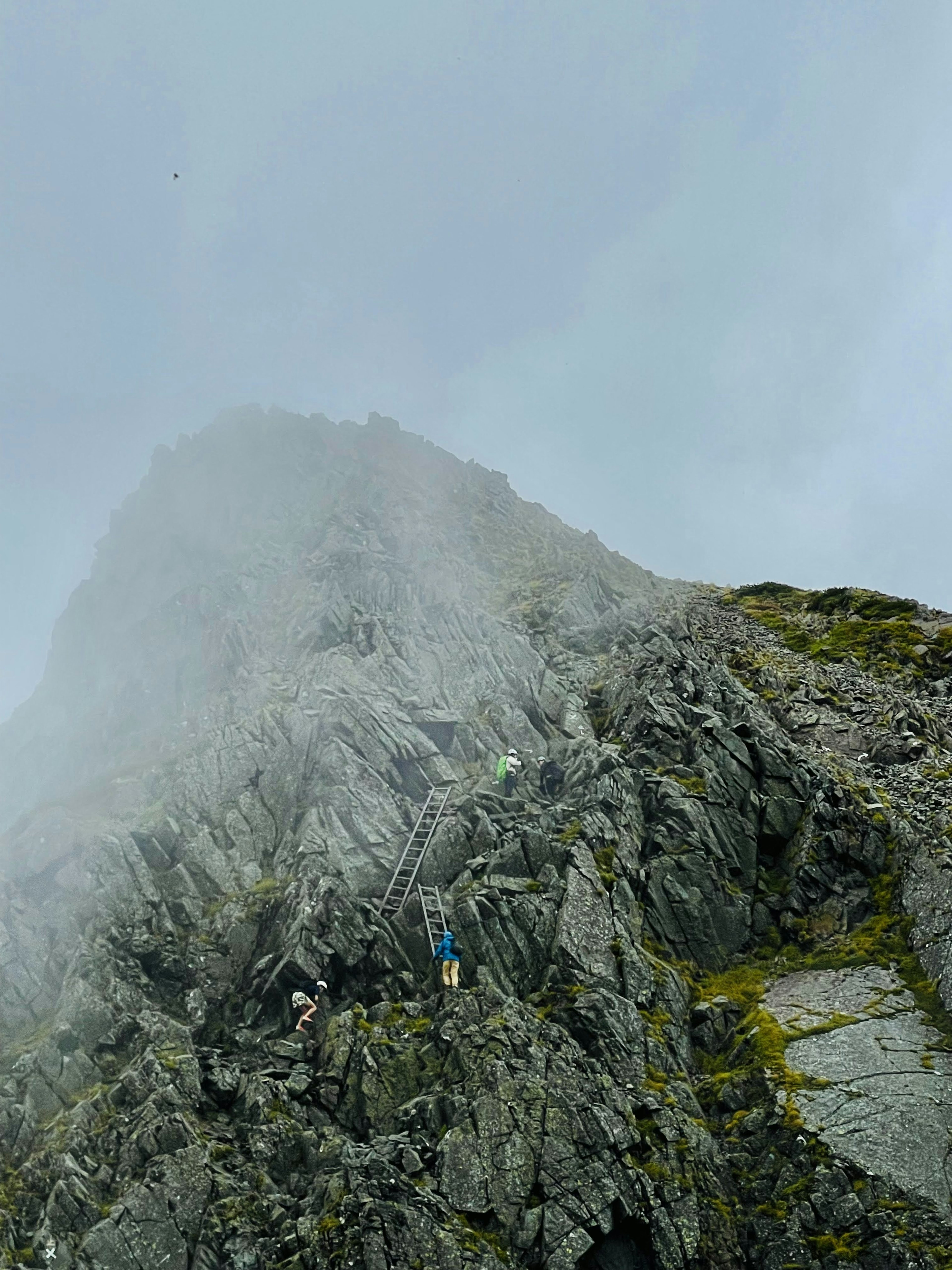 Escaladores ascendiendo a un pico montañoso brumoso