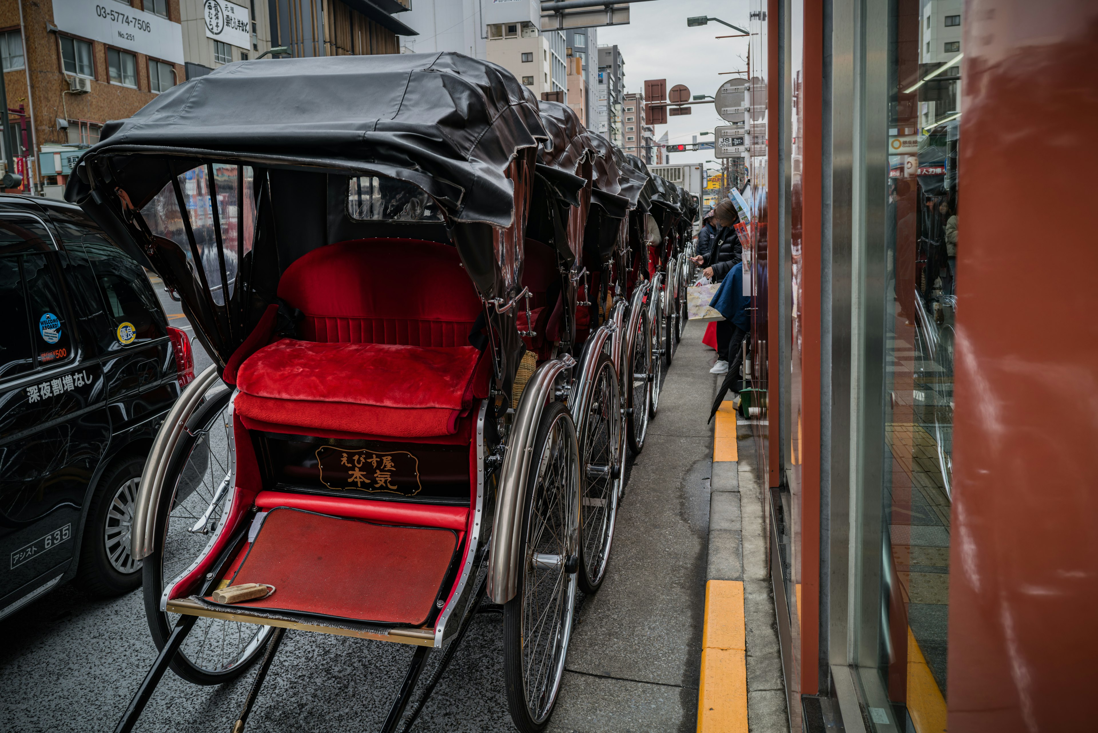 Fila de rickshaws con asientos rojos estacionados en una calle de la ciudad