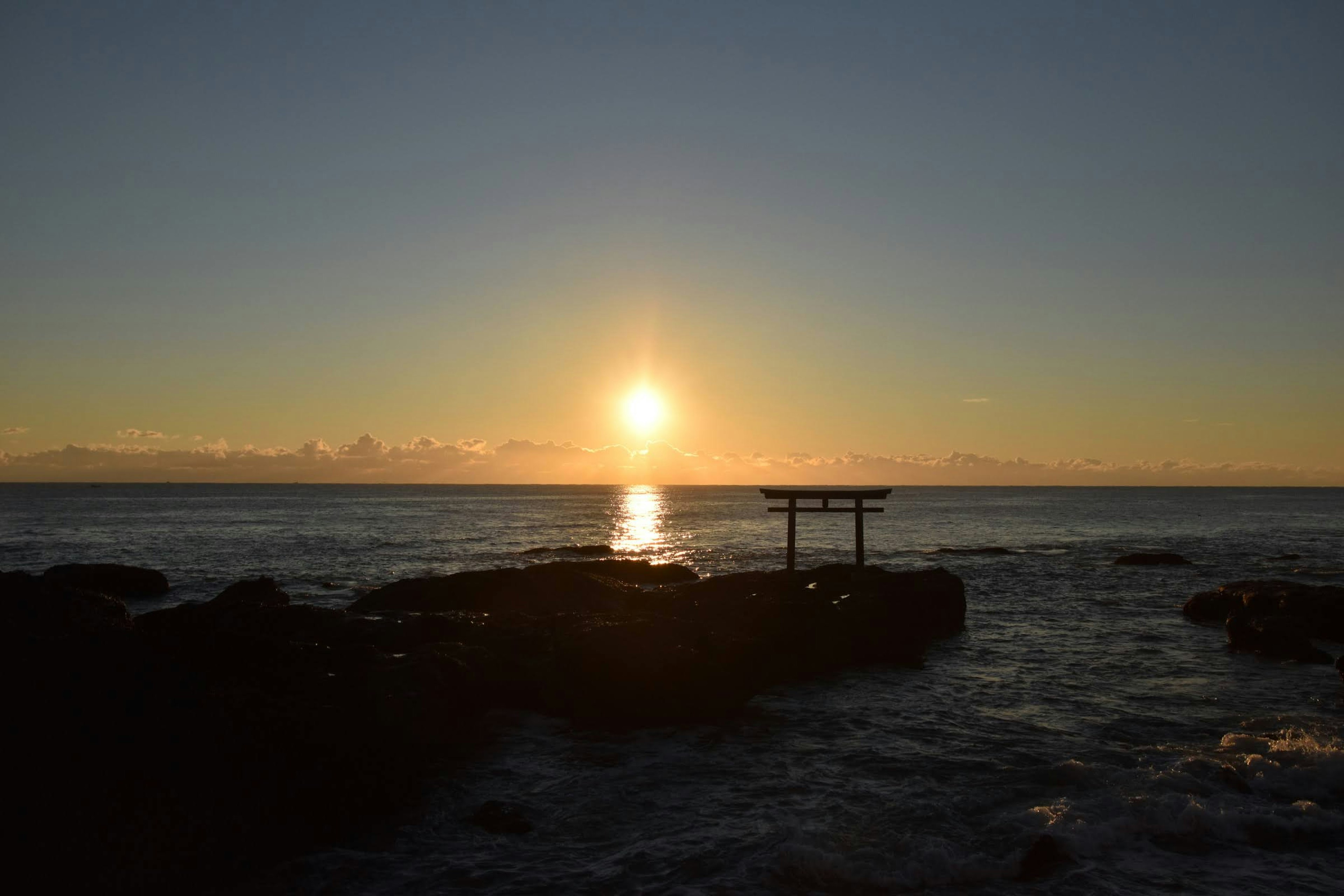 Tramonto sull'oceano con silhouette di rocce