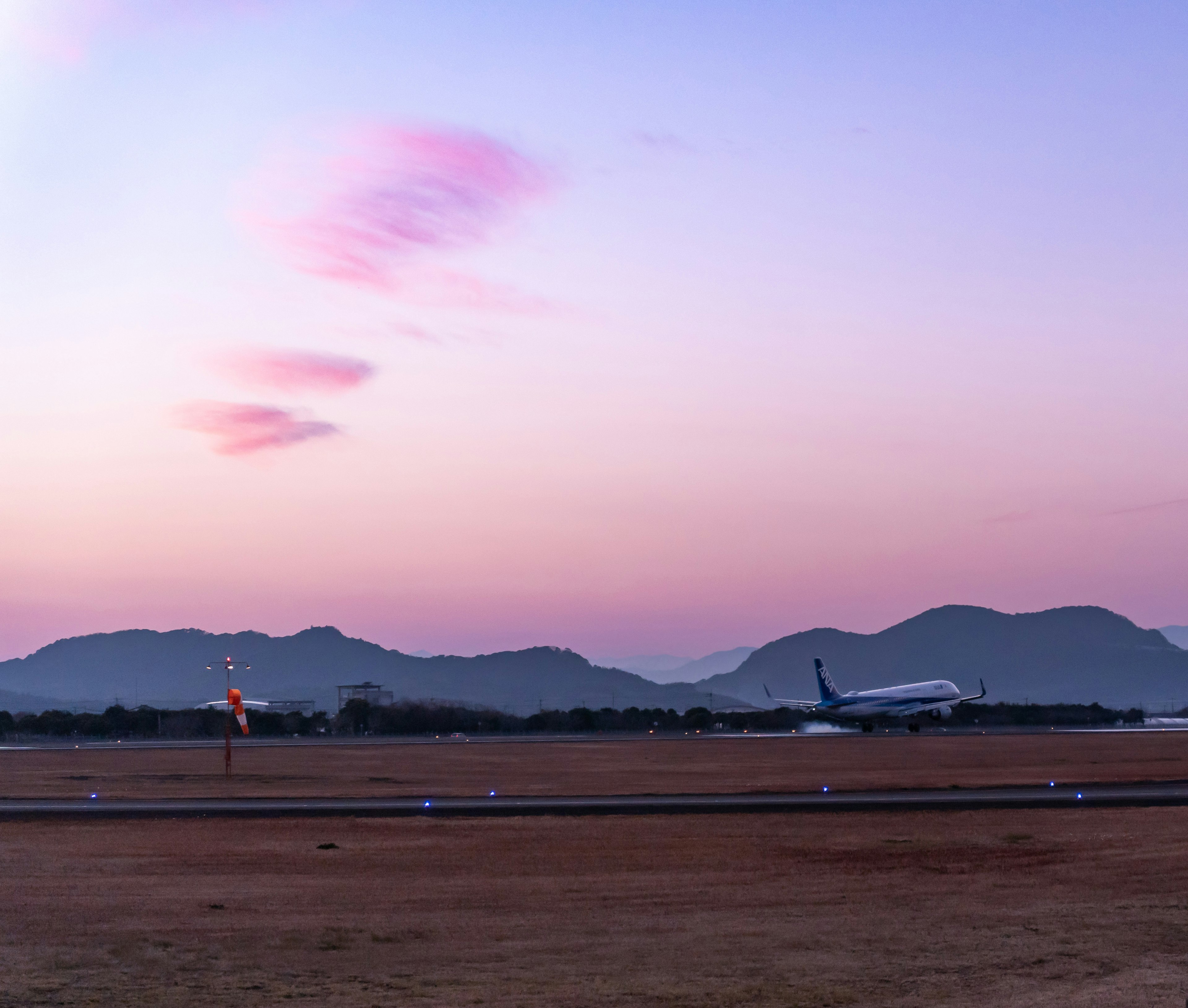 夕焼けの空と山々を背景にした滑走路にいる飛行機のシルエット