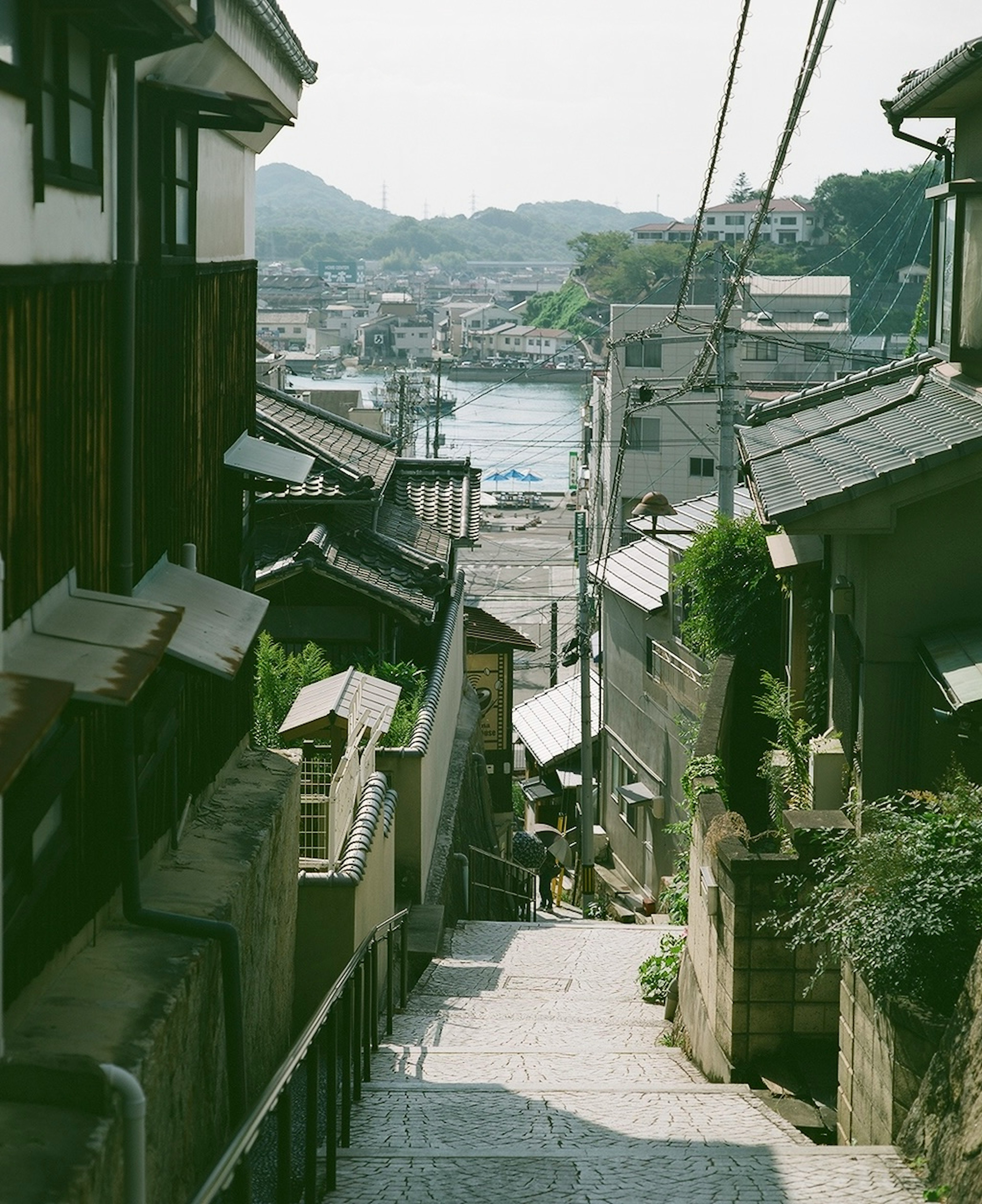 Narrow stone steps leading down through traditional buildings with a view of the sea in the distance