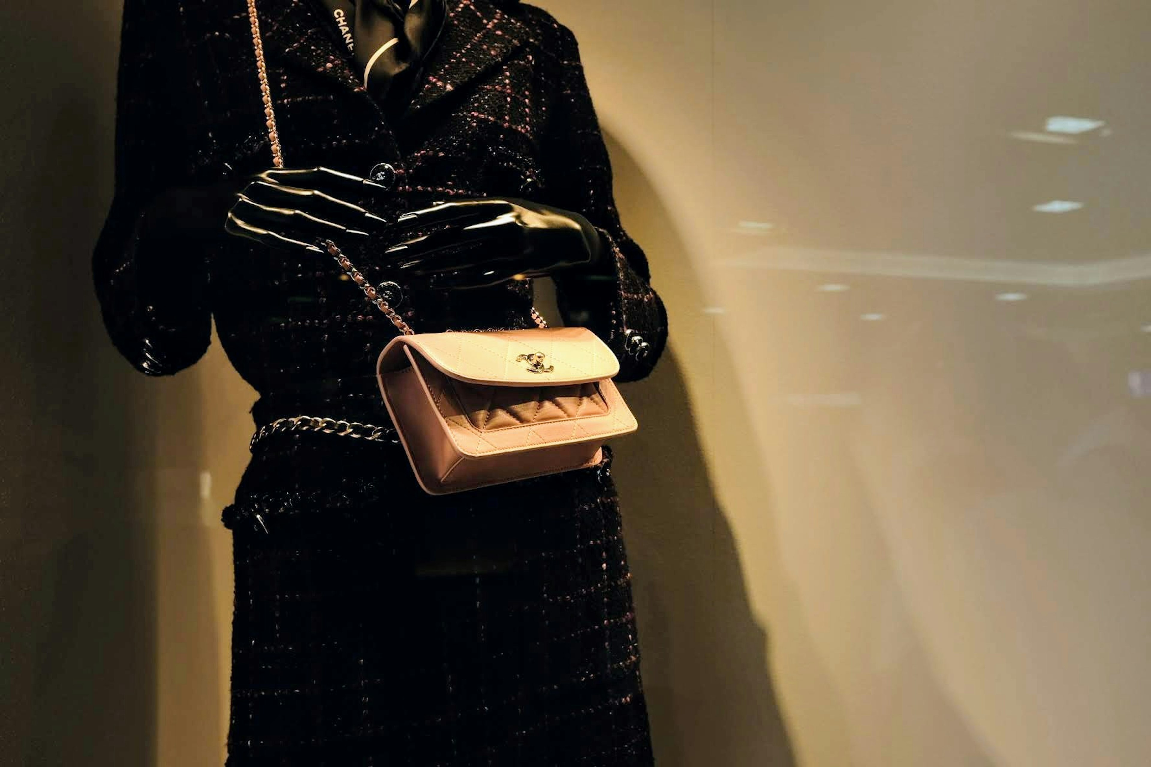 A mannequin dressed in a black suit holding a pink handbag