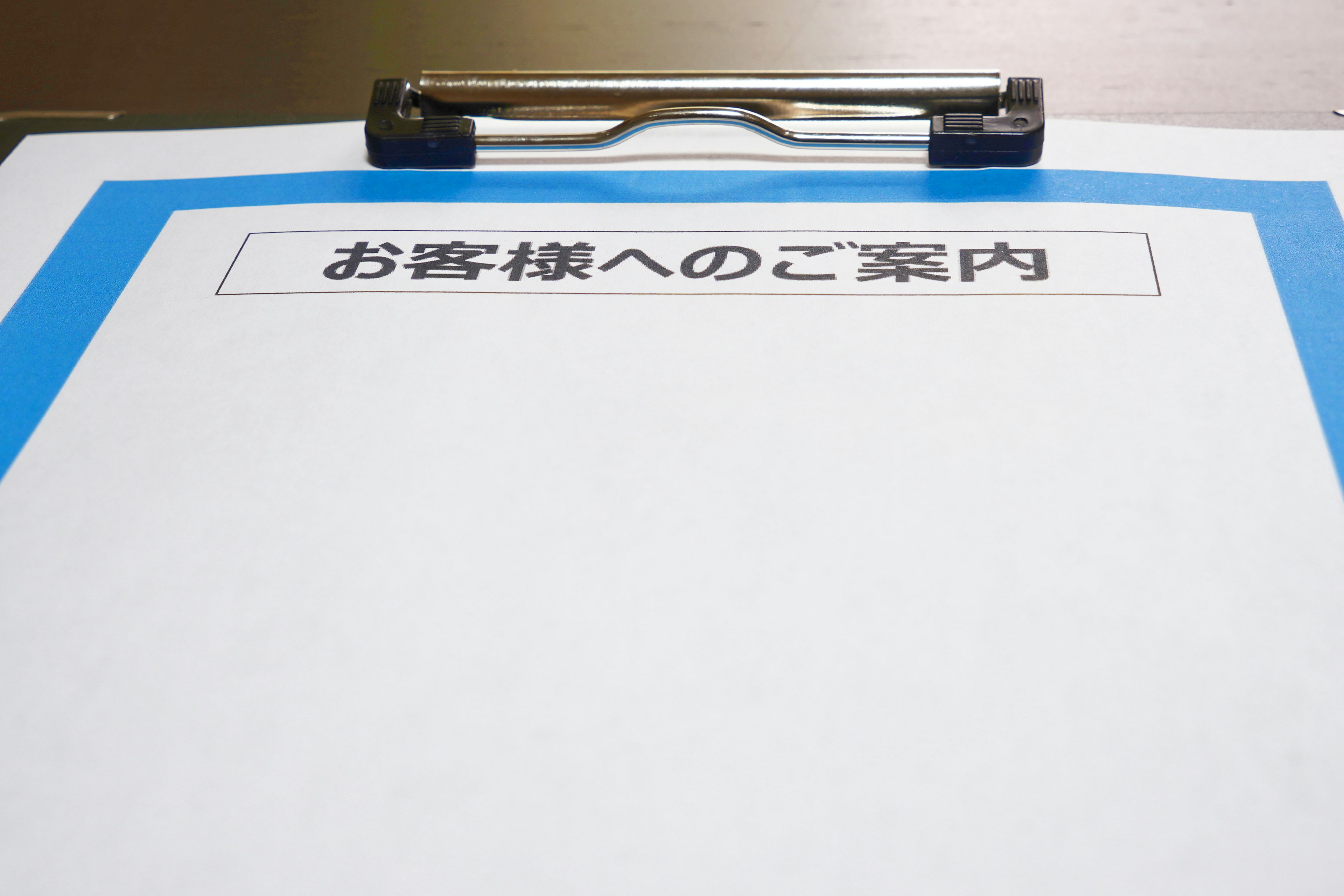 A clipboard with a blue border holding a blank sheet of paper