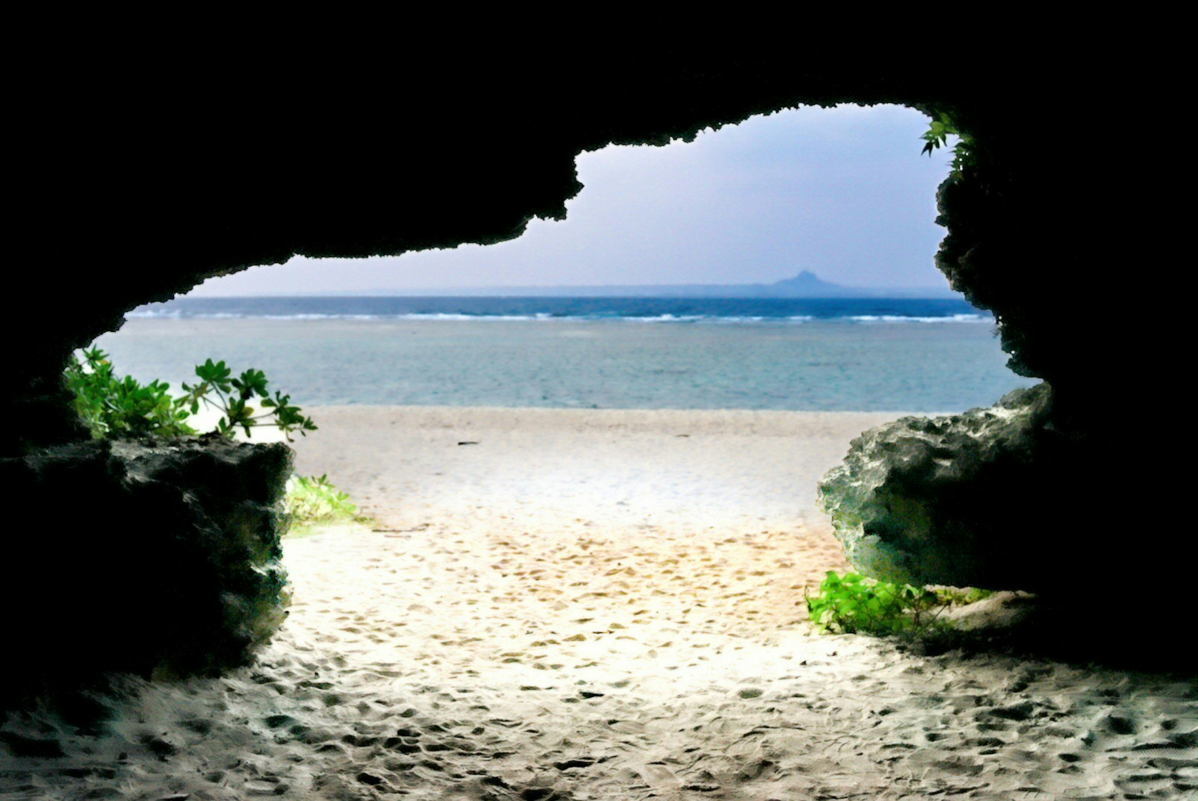 Blick auf einen Strand und den Ozean durch eine Höhlenöffnung