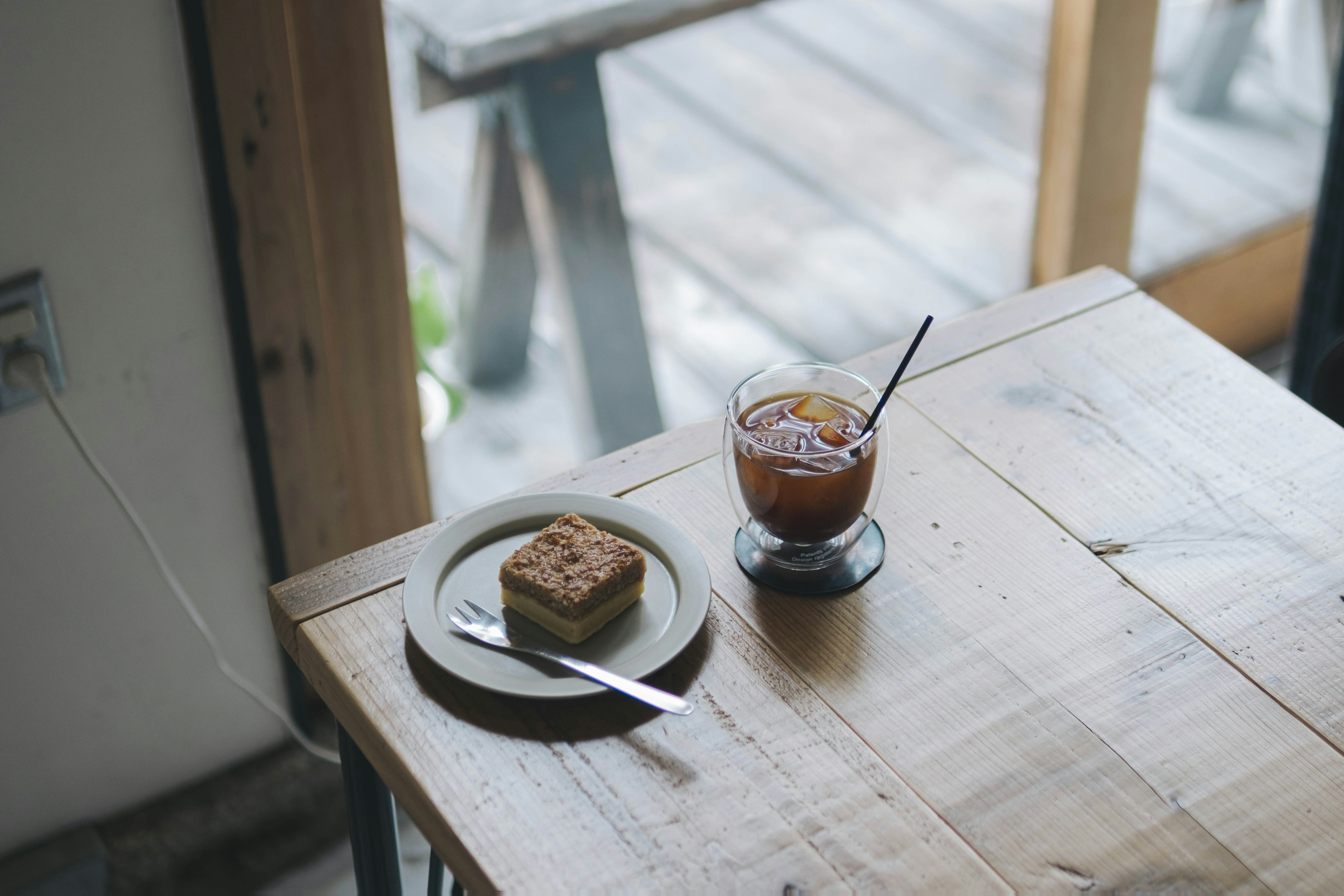 A slice of cake and iced tea on a wooden table