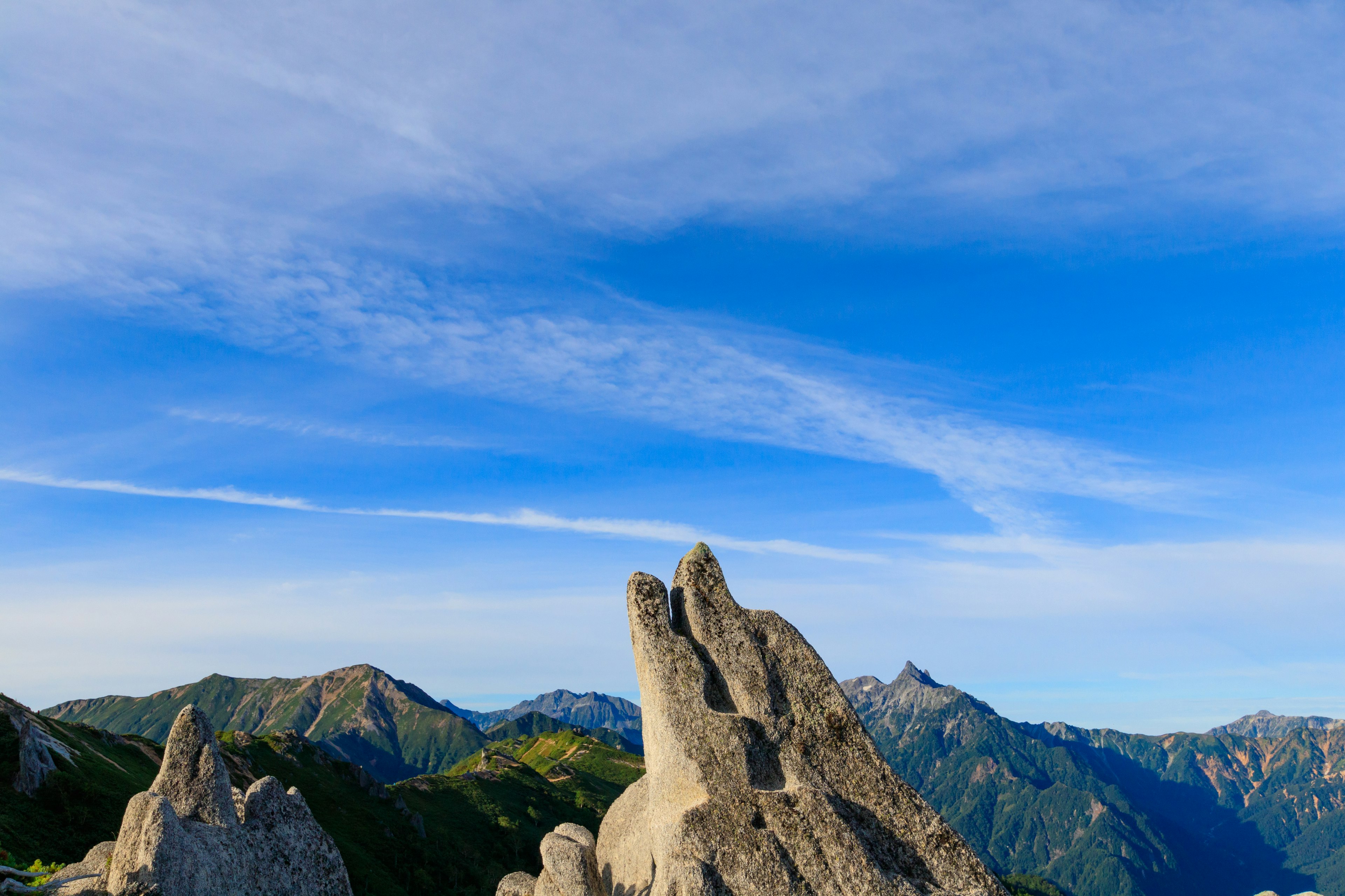 Picos rocosos bajo un cielo azul claro con montañas distantes