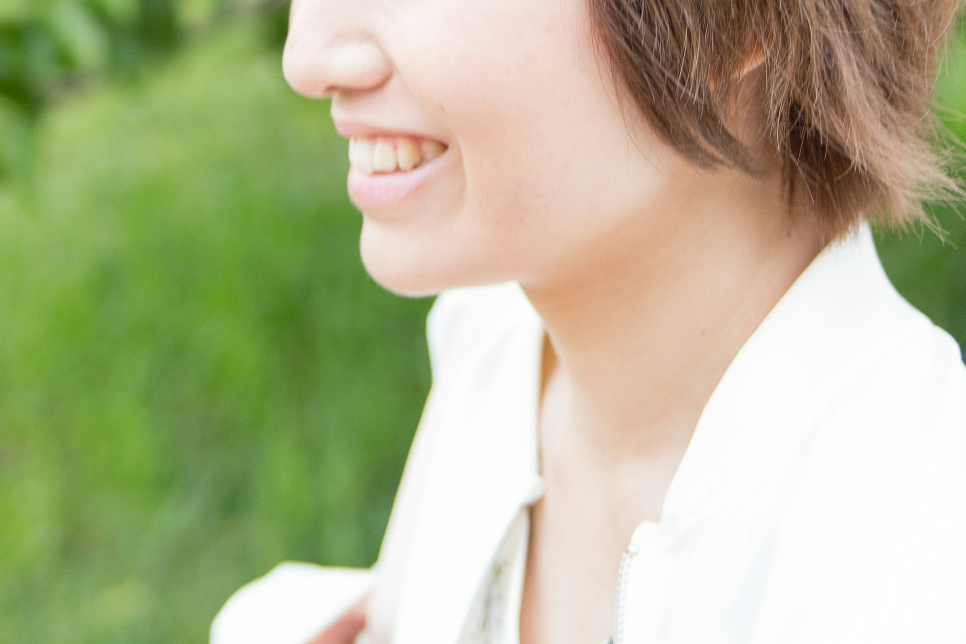 Side profile of a smiling woman against a green background