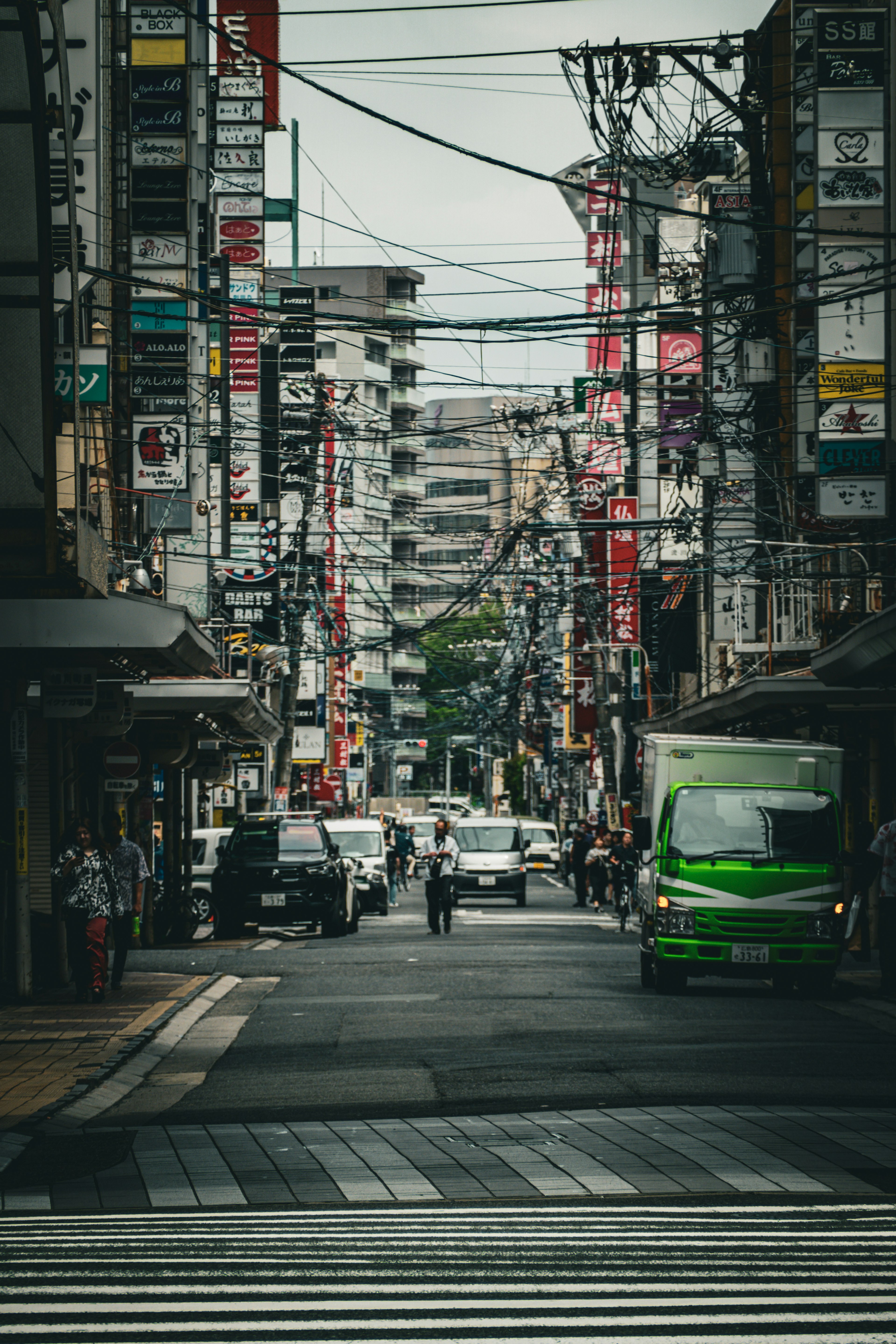 Urban street scene with people and cars bustling between buildings