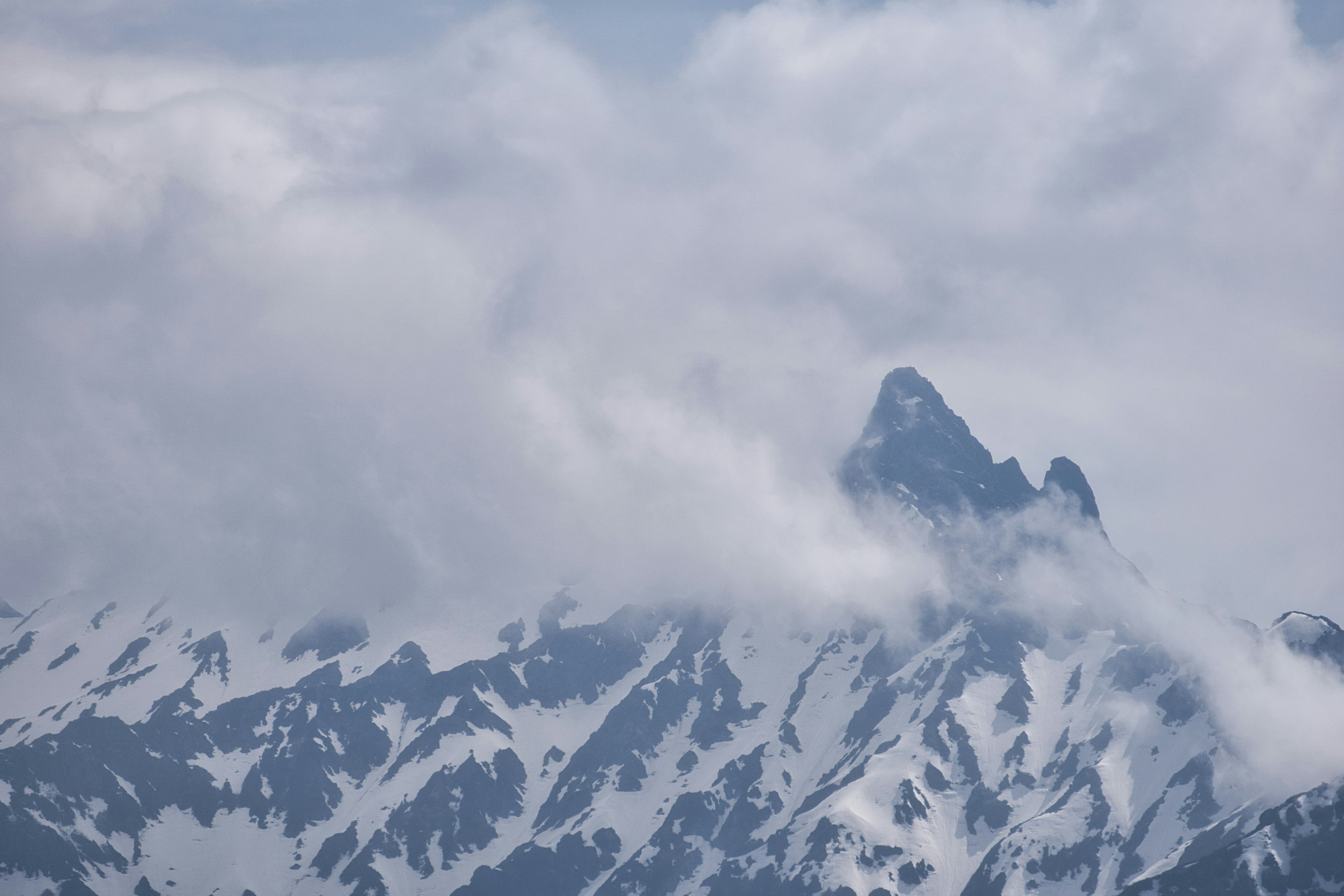 Snow-covered mountains with a peak hidden in clouds