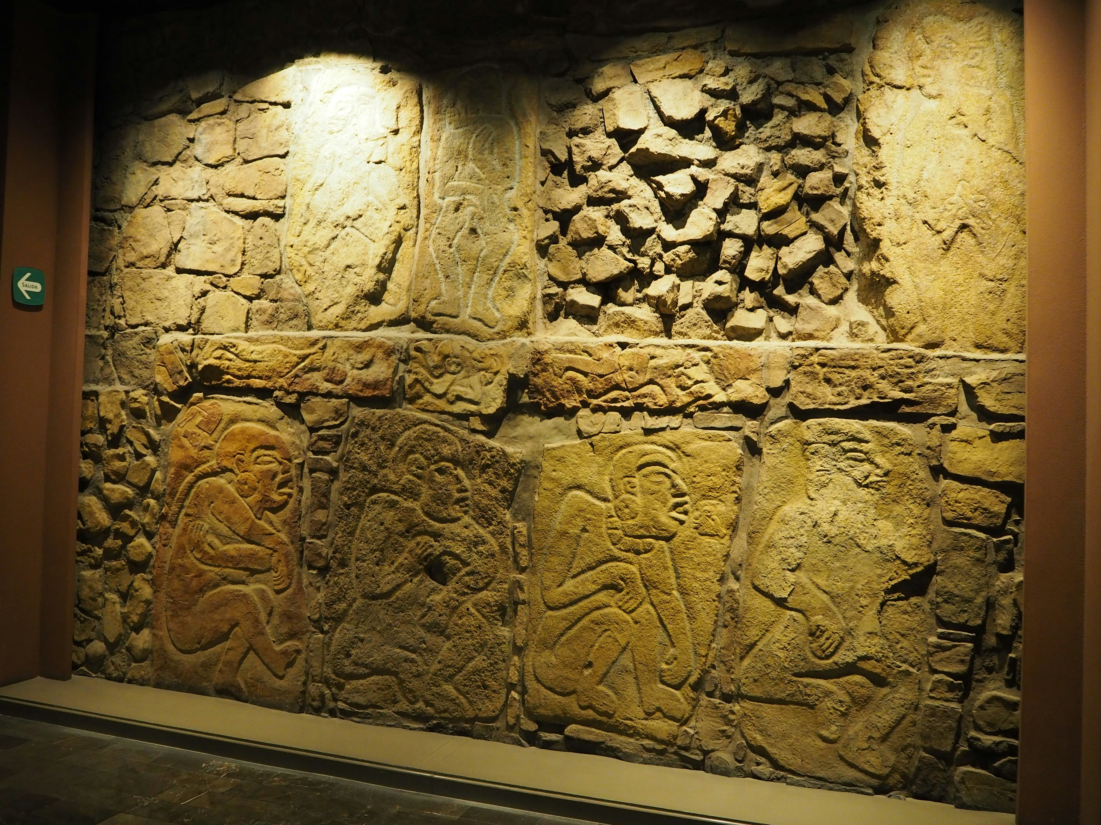 Wall display featuring stone carvings with ancient artistic elements highlighted by lighting