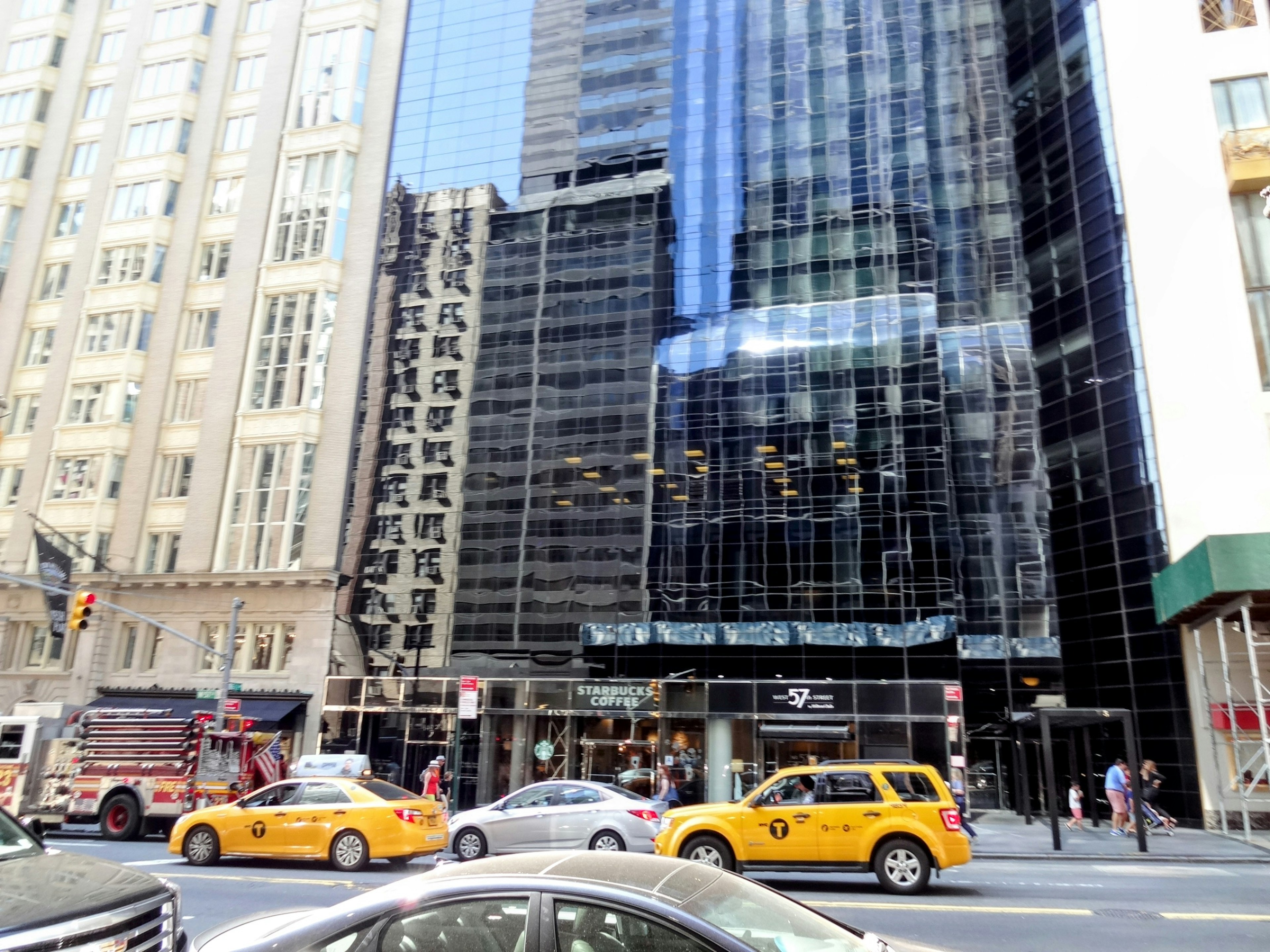 Urban scene featuring skyscraper reflections and yellow taxis