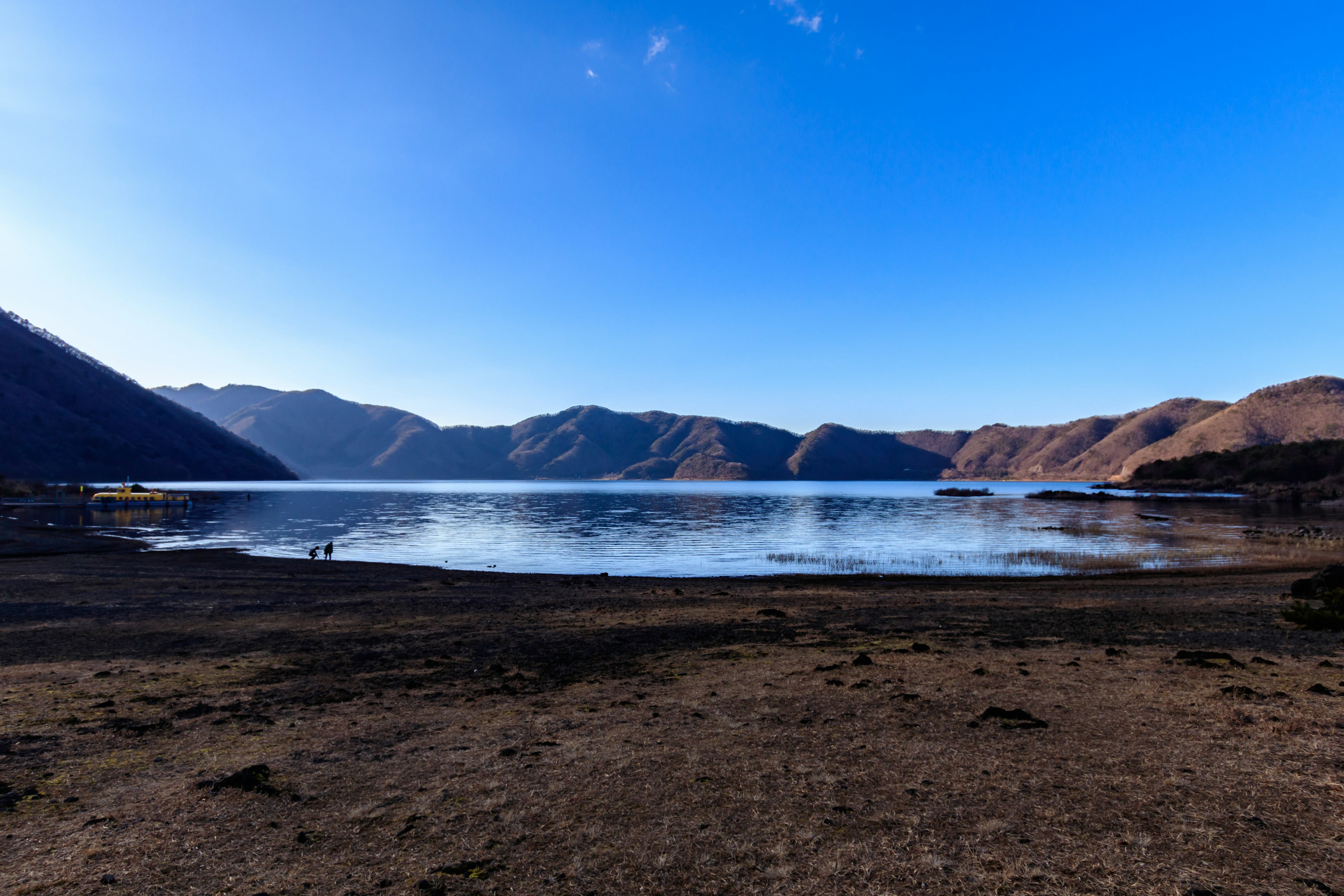 Lago sereno circondato da montagne sotto un cielo blu chiaro