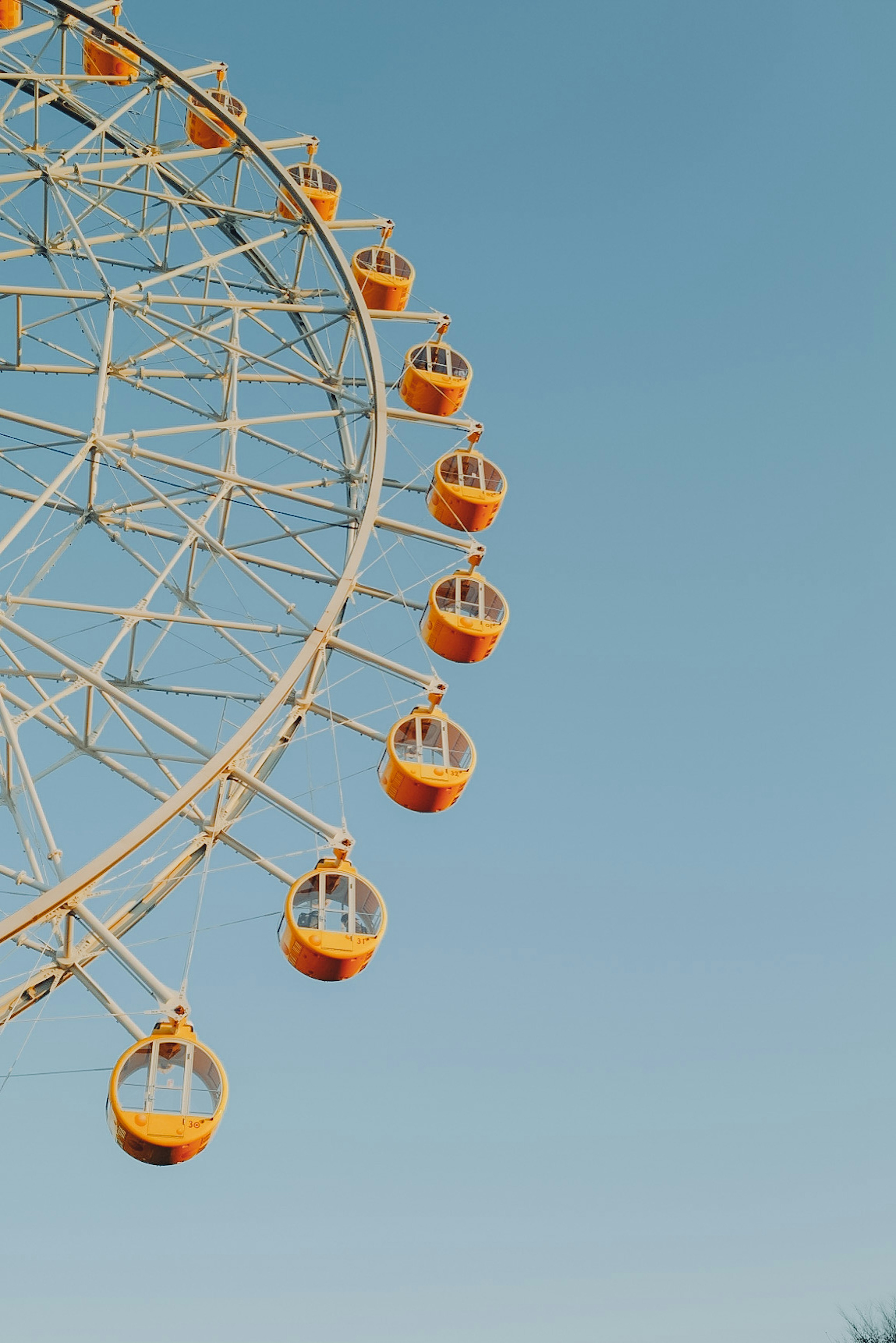 Partie d'une grande roue sous un ciel bleu avec des gondoles jaunes