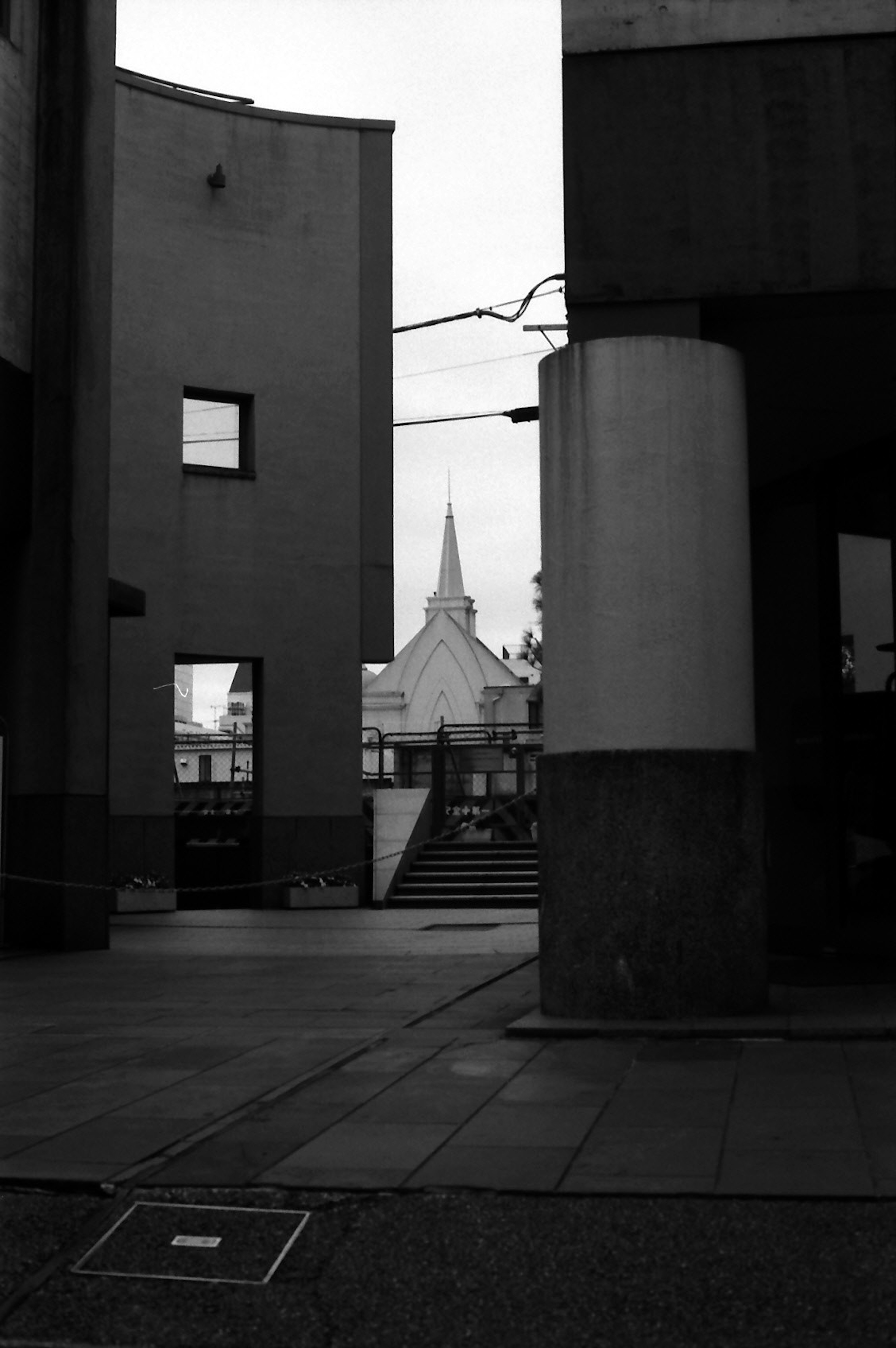 Aguja de iglesia visible a través de la arquitectura urbana en blanco y negro