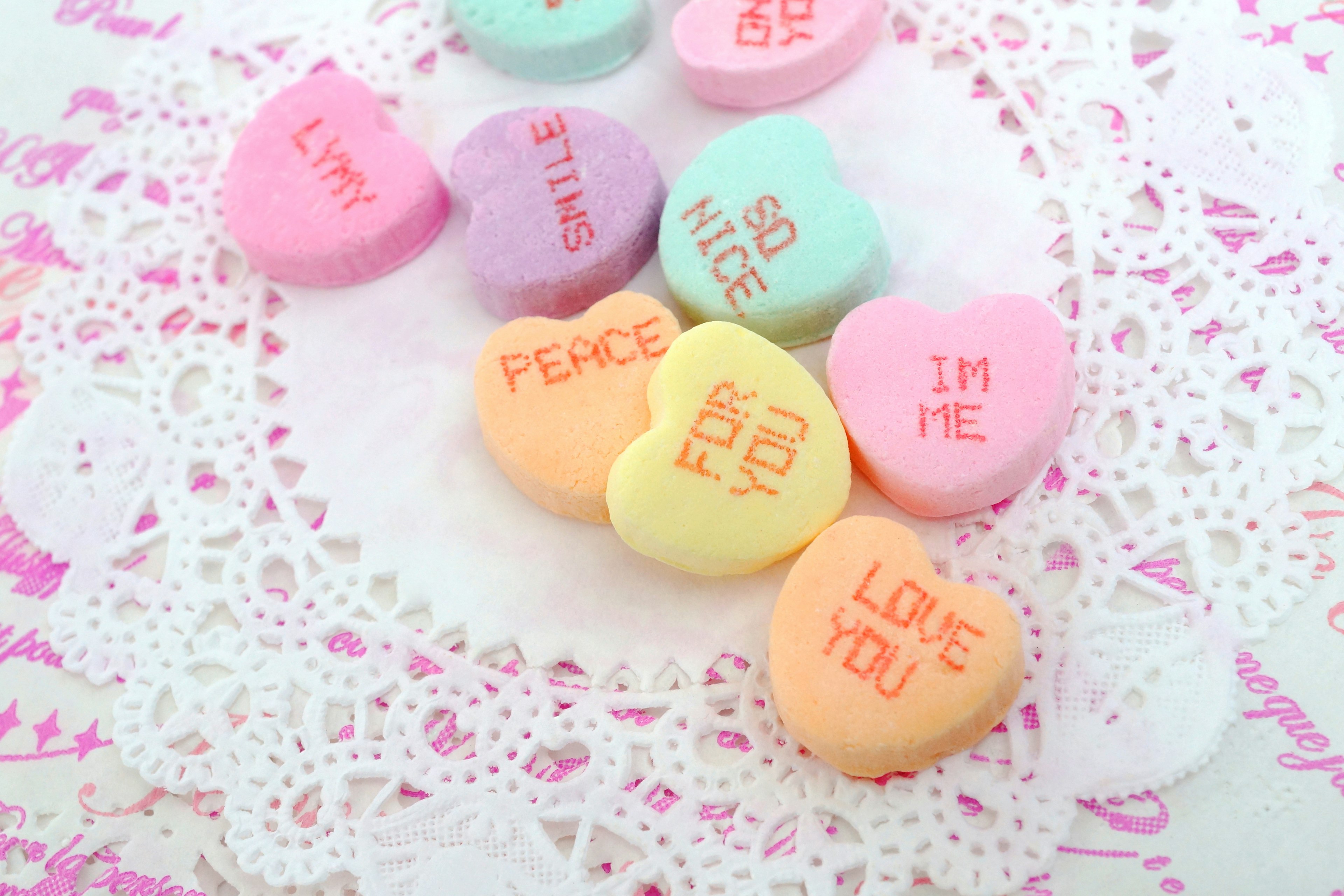 Bonbons en forme de cœur colorés disposés sur une nappe en dentelle