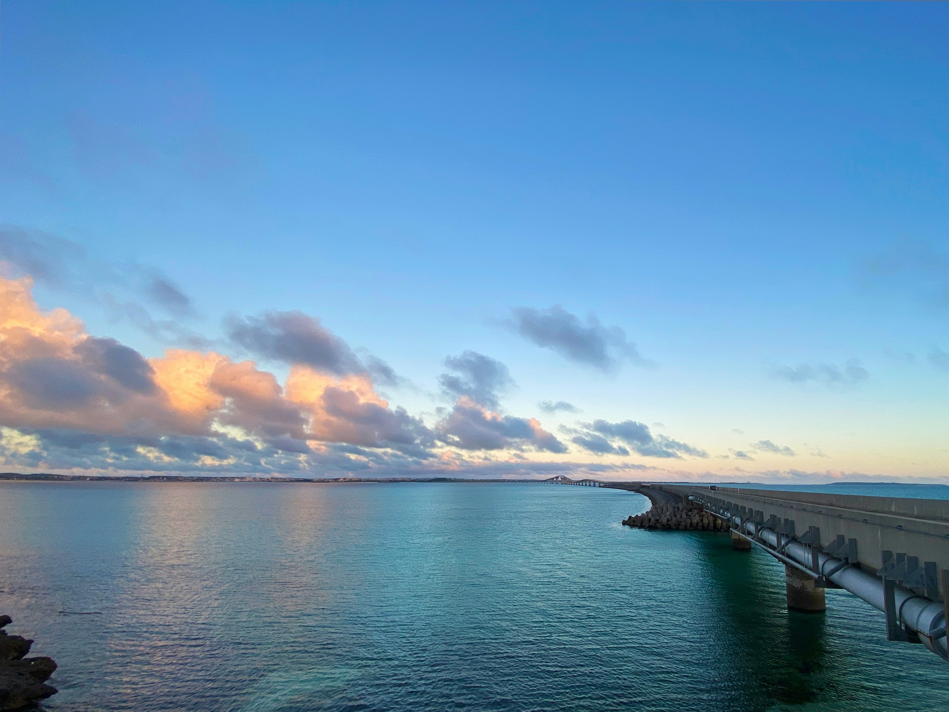 Una vista panoramica di un lungo molo contro un cielo blu e acqua calma