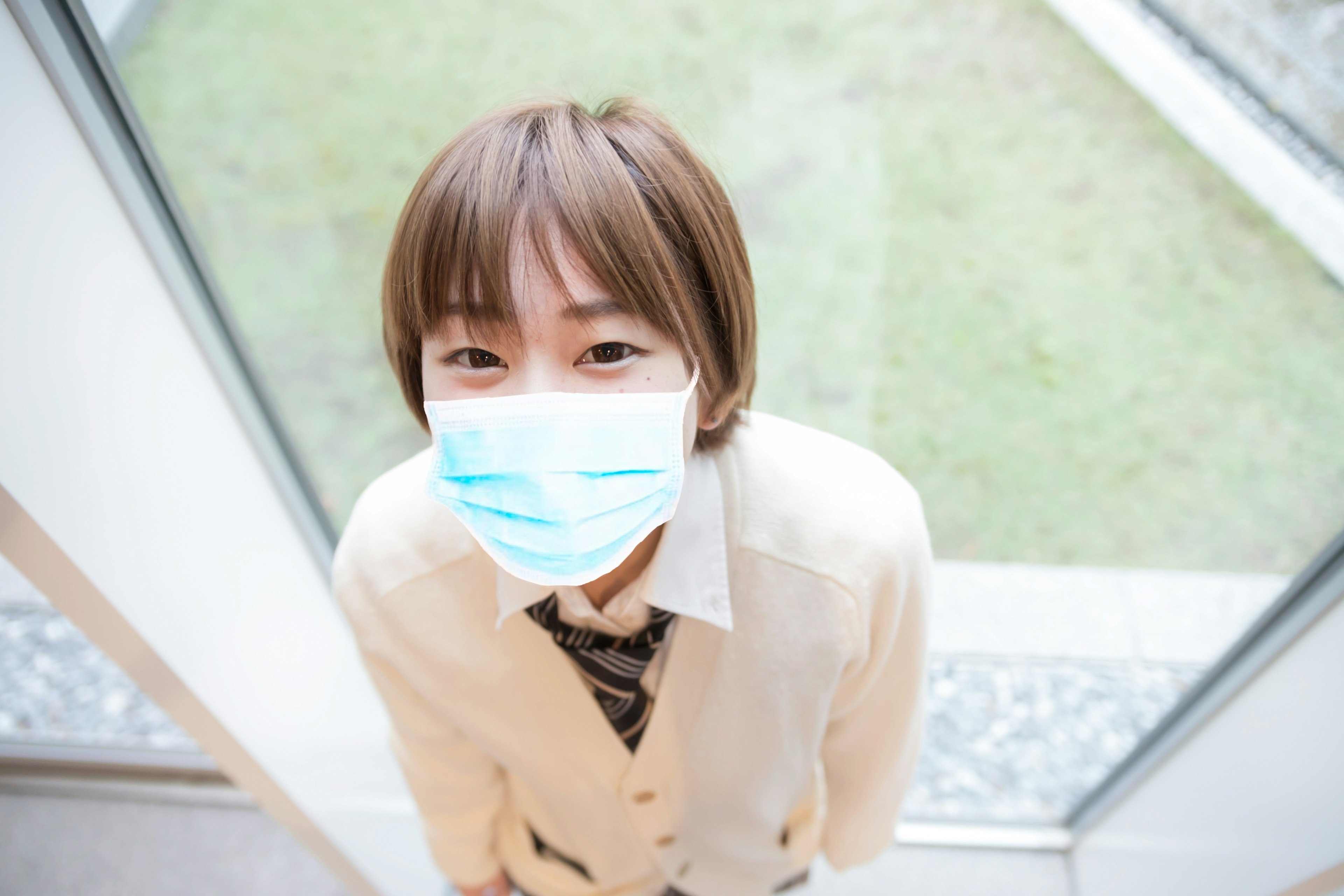 Mujer sonriendo con mascarilla cerca de una ventana