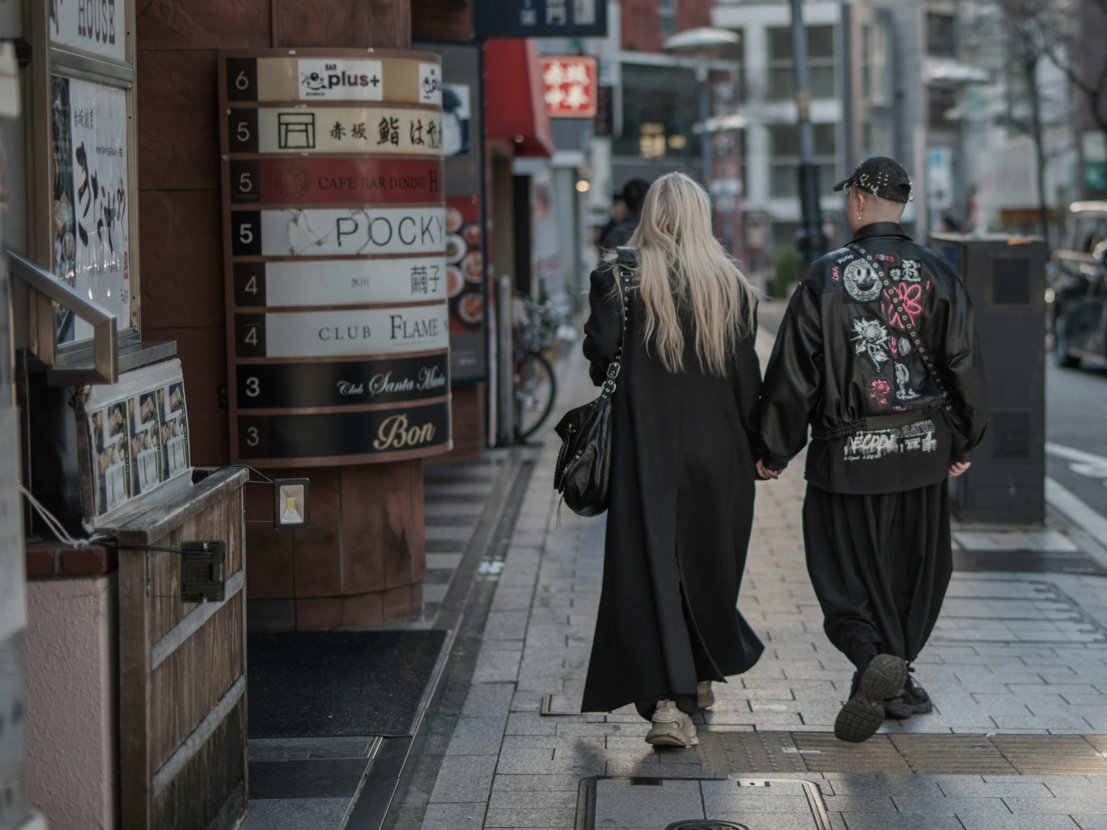 Two young people walking hand in hand on a city street