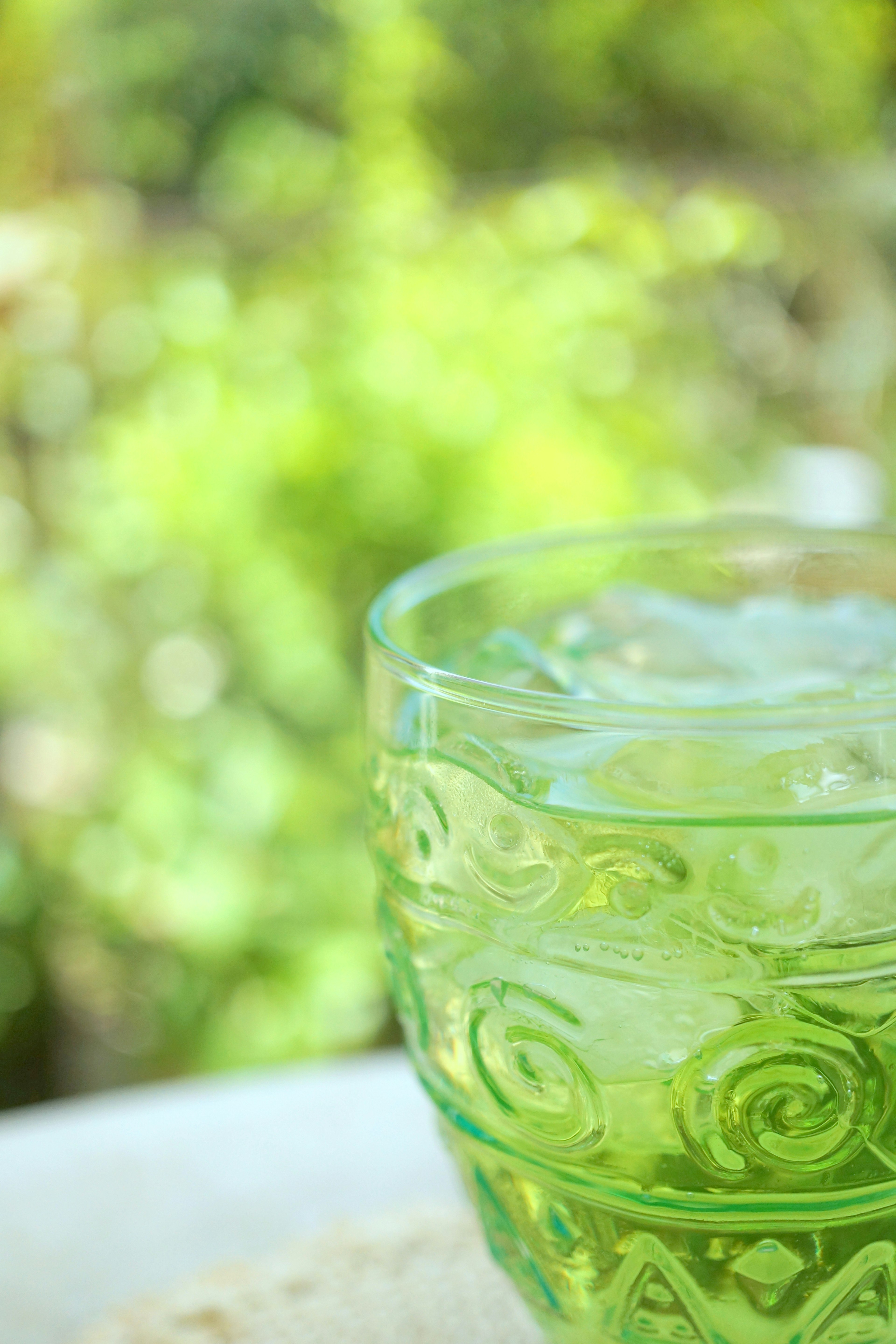 Verre en verre vert rempli de glace avec un arrière-plan flou en extérieur