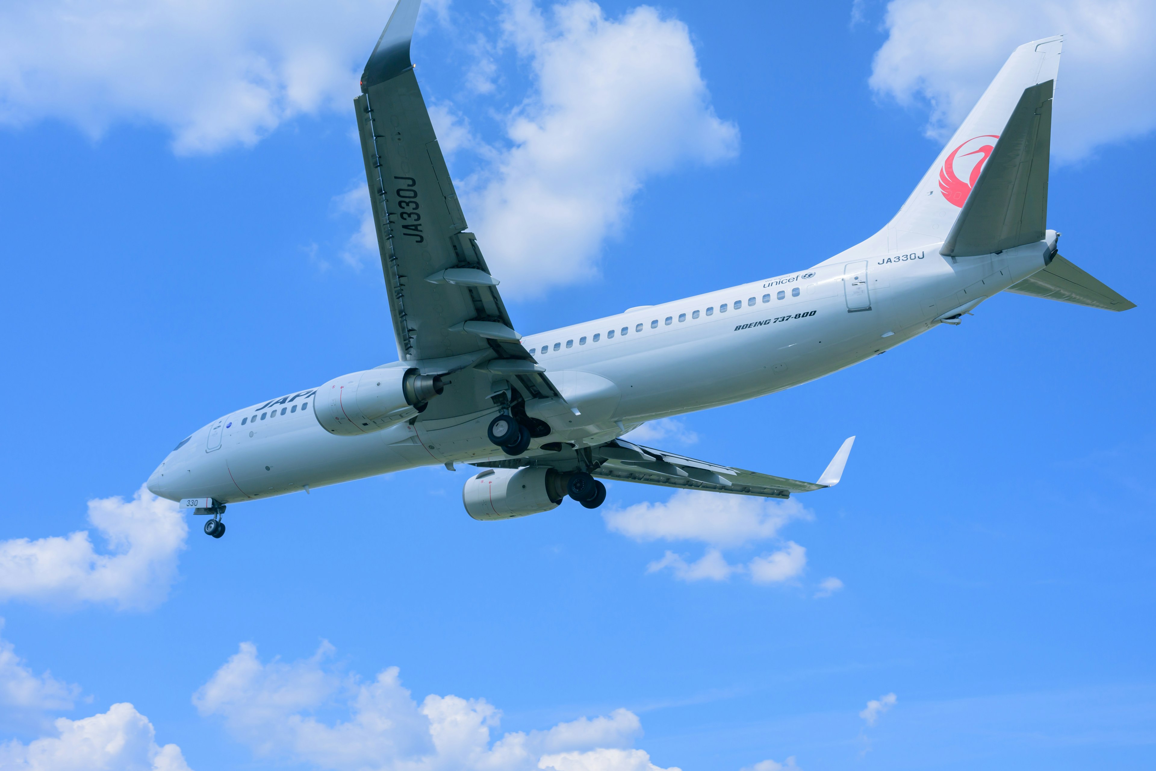 青空の中を飛ぶ航空機の写真