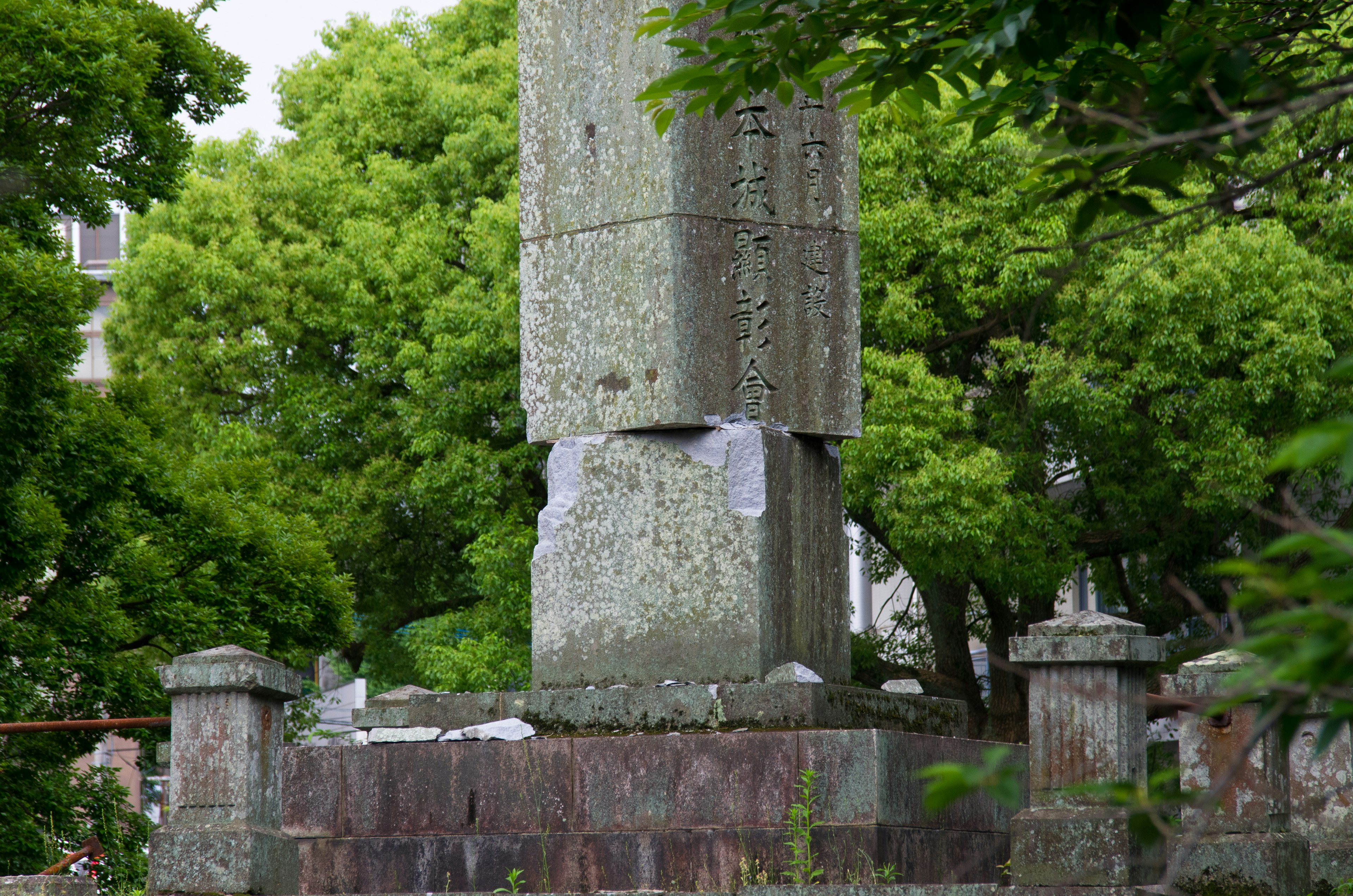 An old stone monument surrounded by green trees