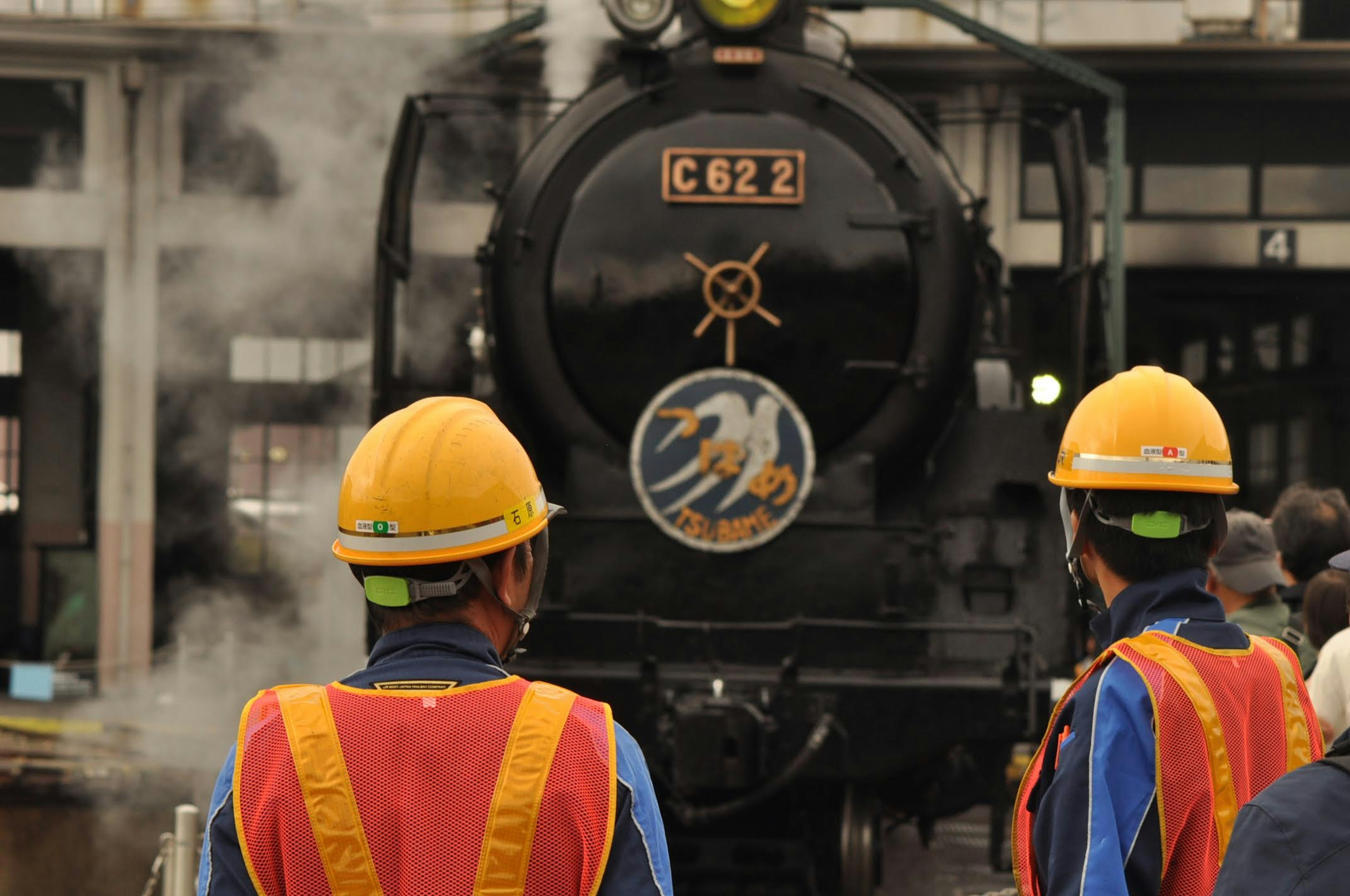 Des travailleurs observant la locomotive à vapeur C622 dans une gare