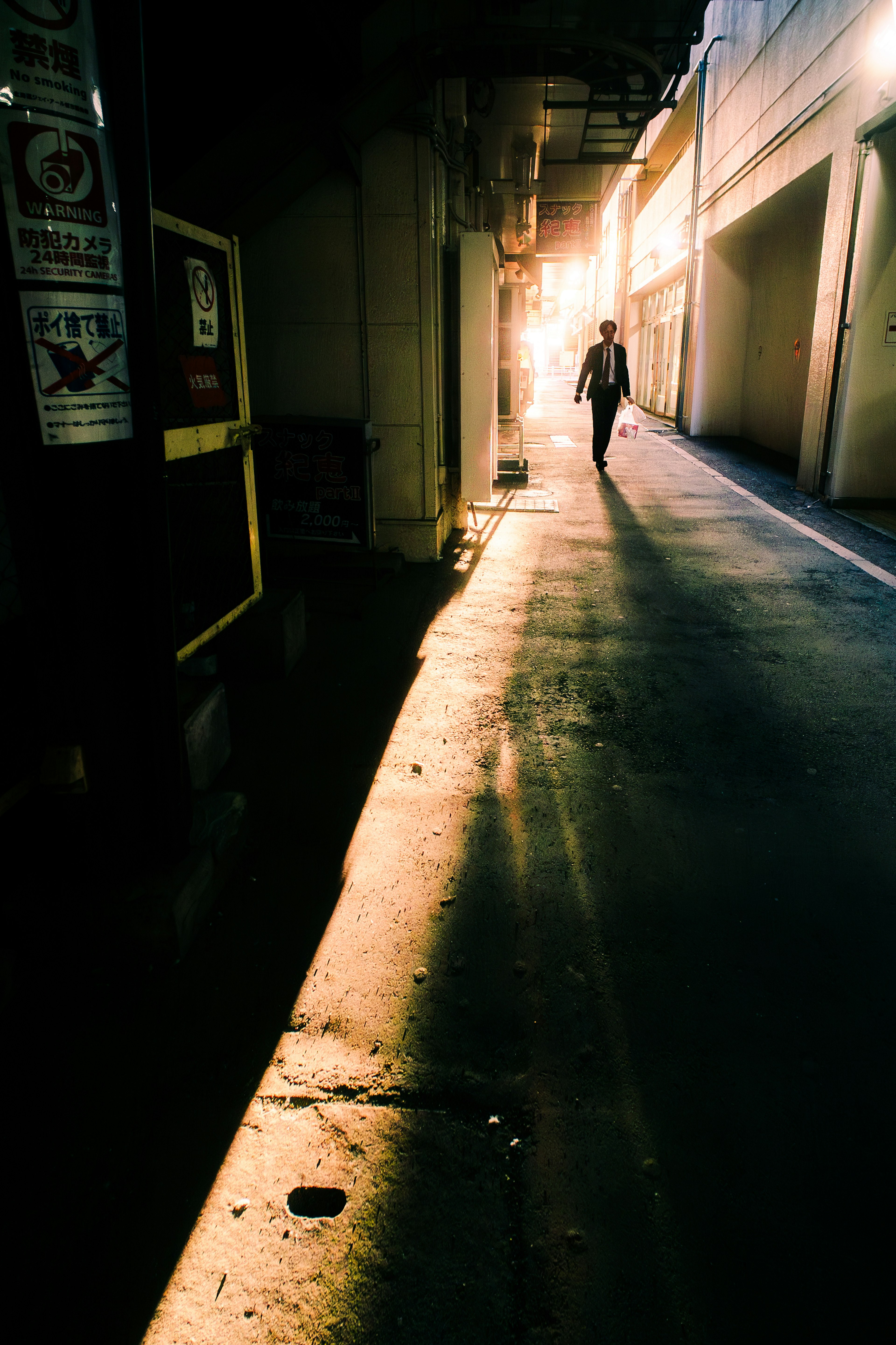 薄暗い路地に人が歩いている光景 光が差し込む