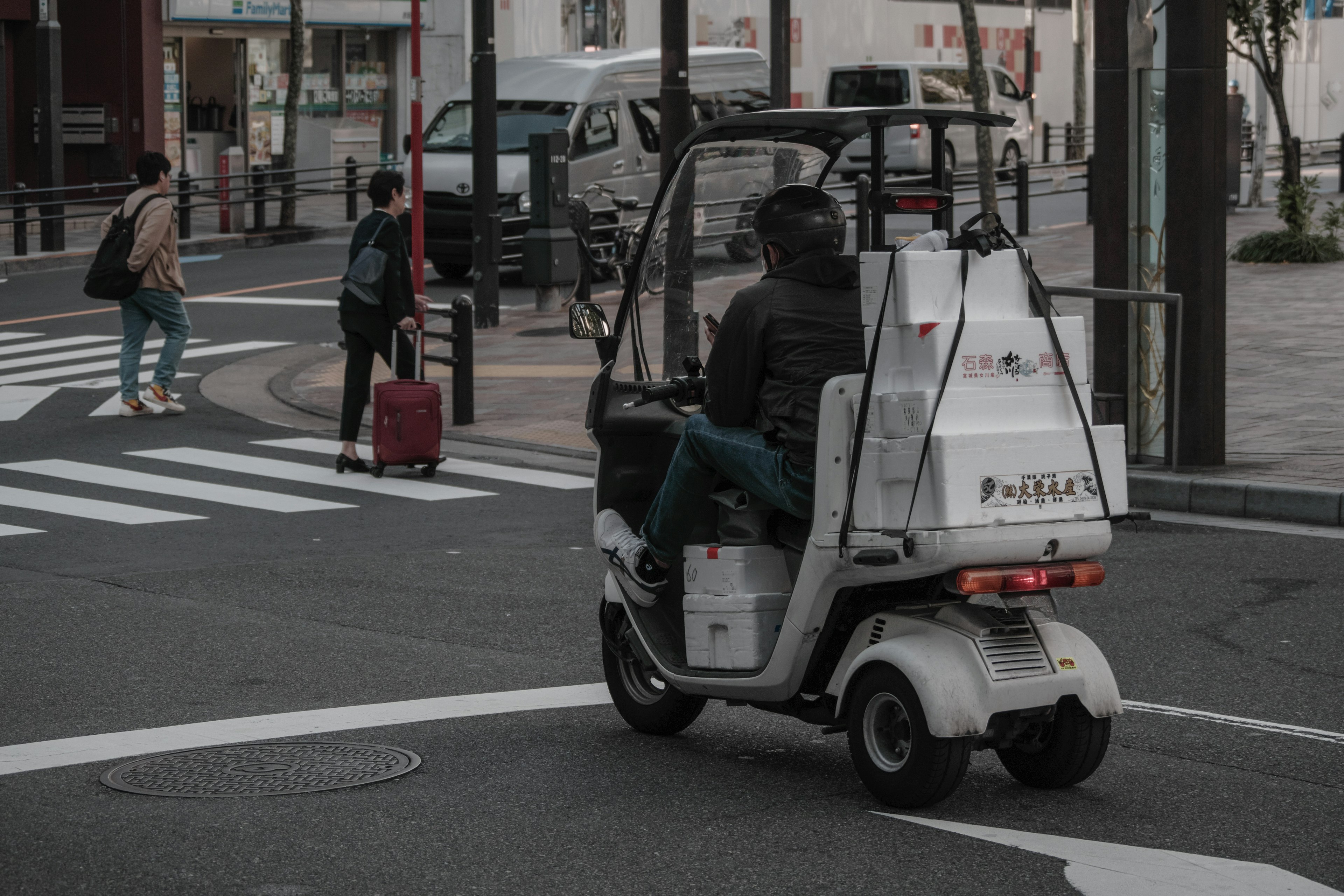 交差点を曲がる電動三輪車と歩行者