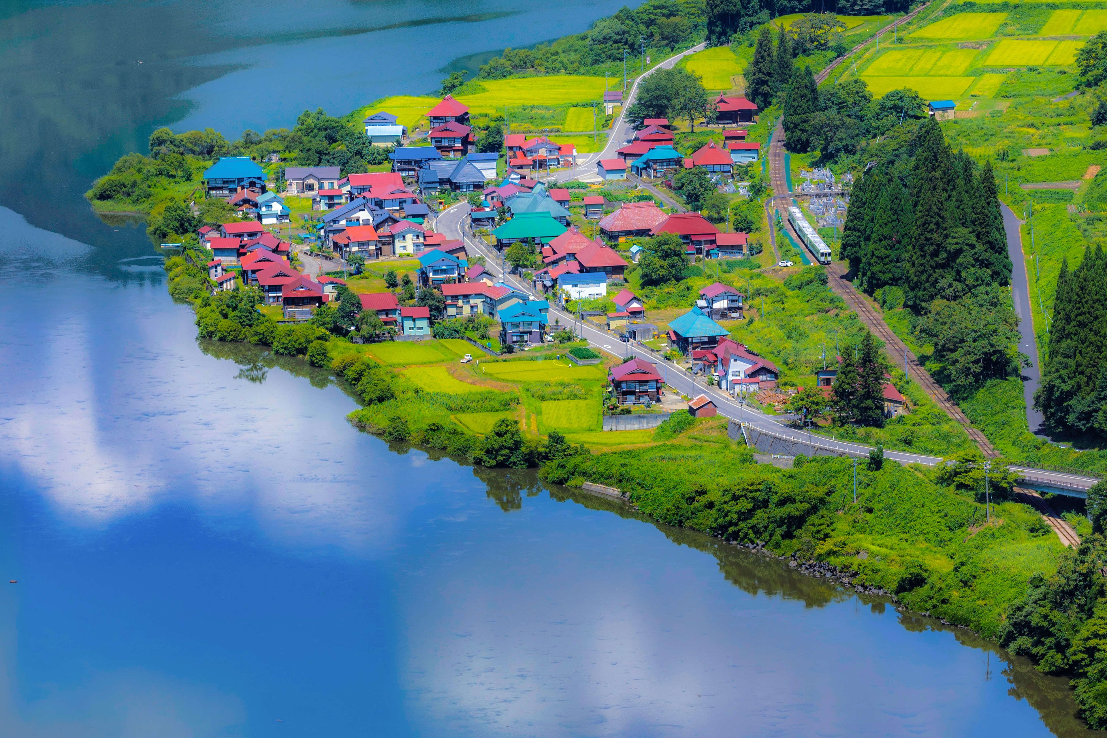 美しい湖のほとりにあるカラフルな村の風景 緑豊かな田んぼと色とりどりの家々