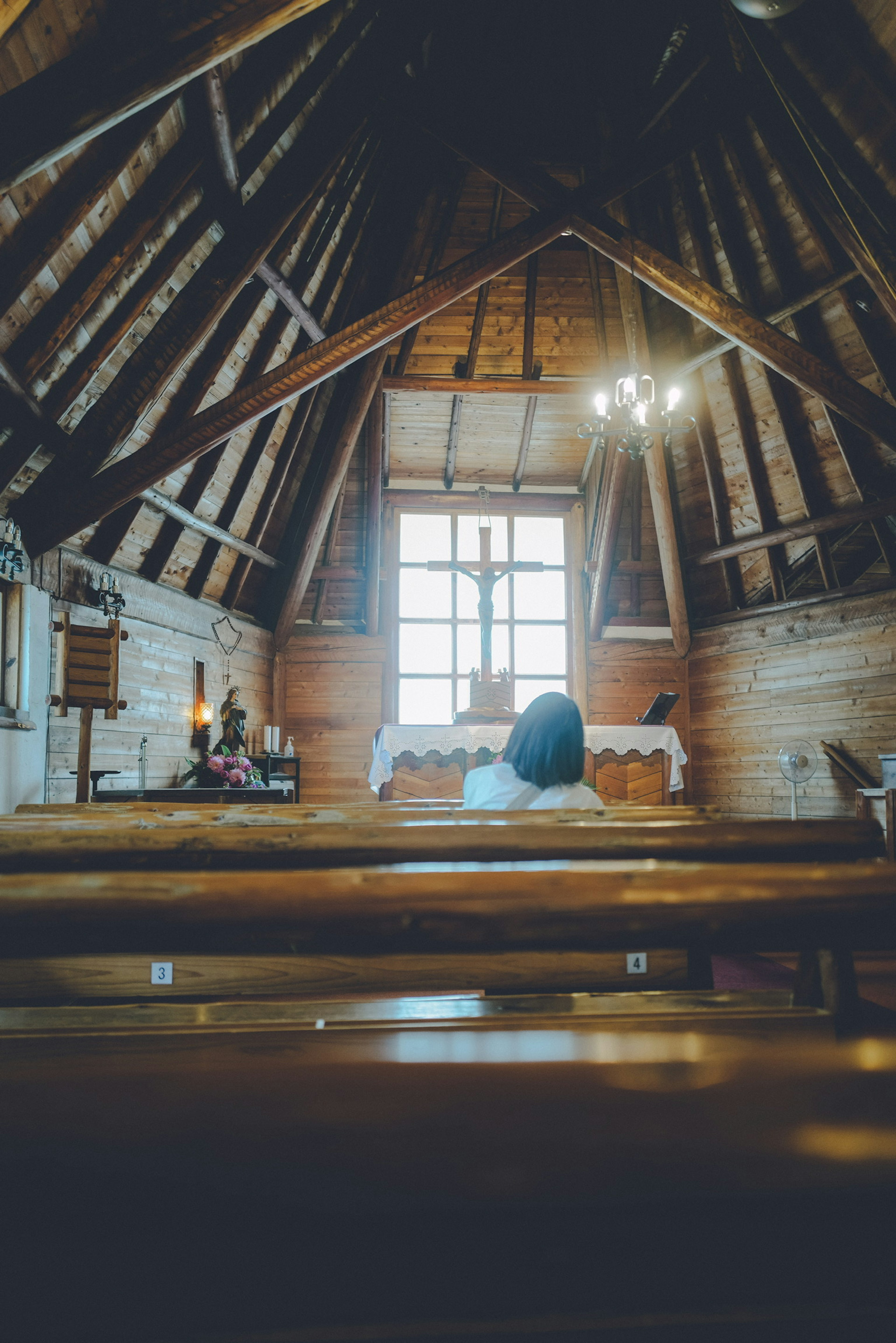 Interior de una iglesia de madera con una gran ventana y una atmósfera serena