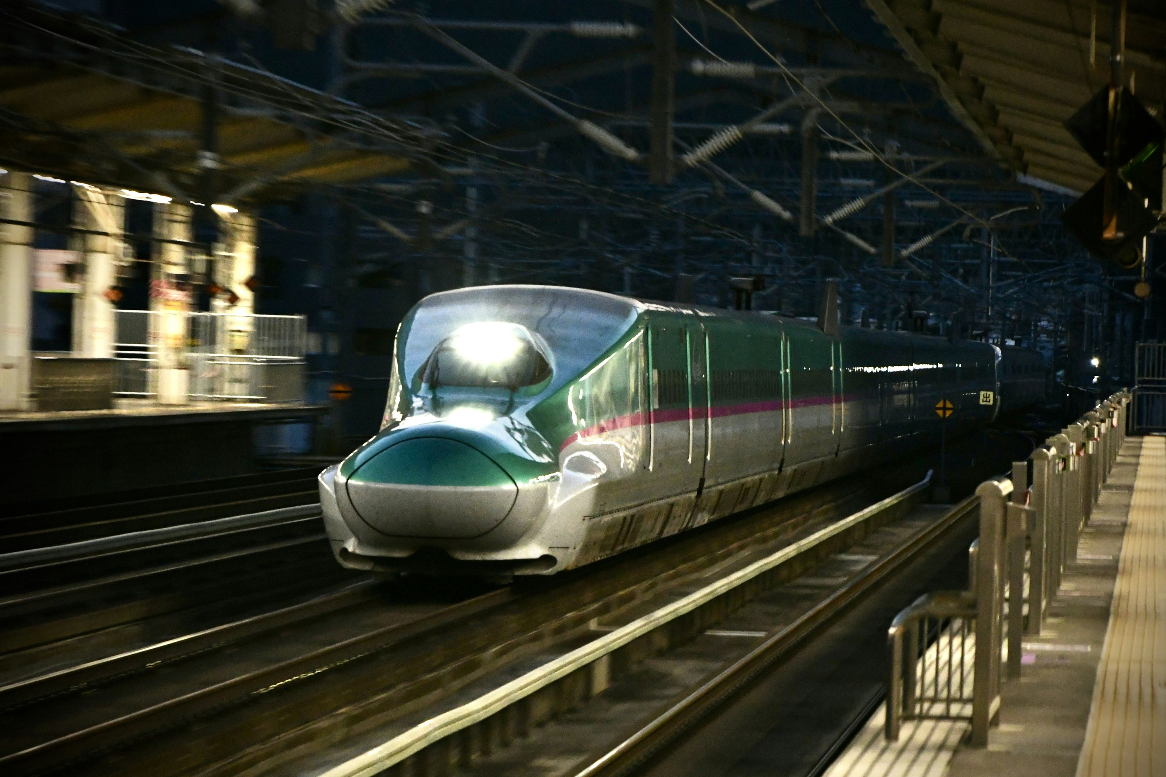 Shinkansen arriving at a station showcasing speed and lighting at night