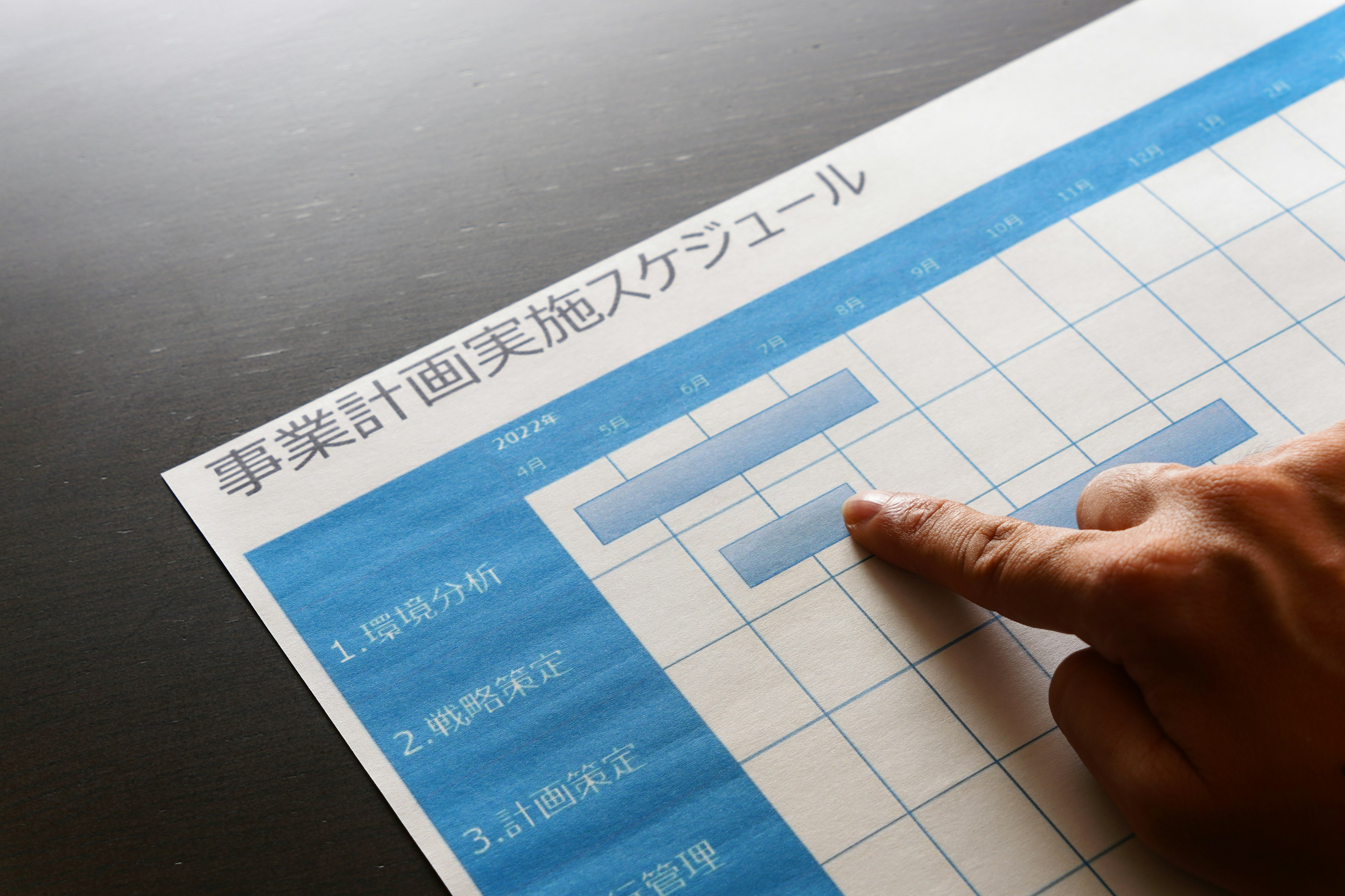 A hand pointing at a blue schedule chart