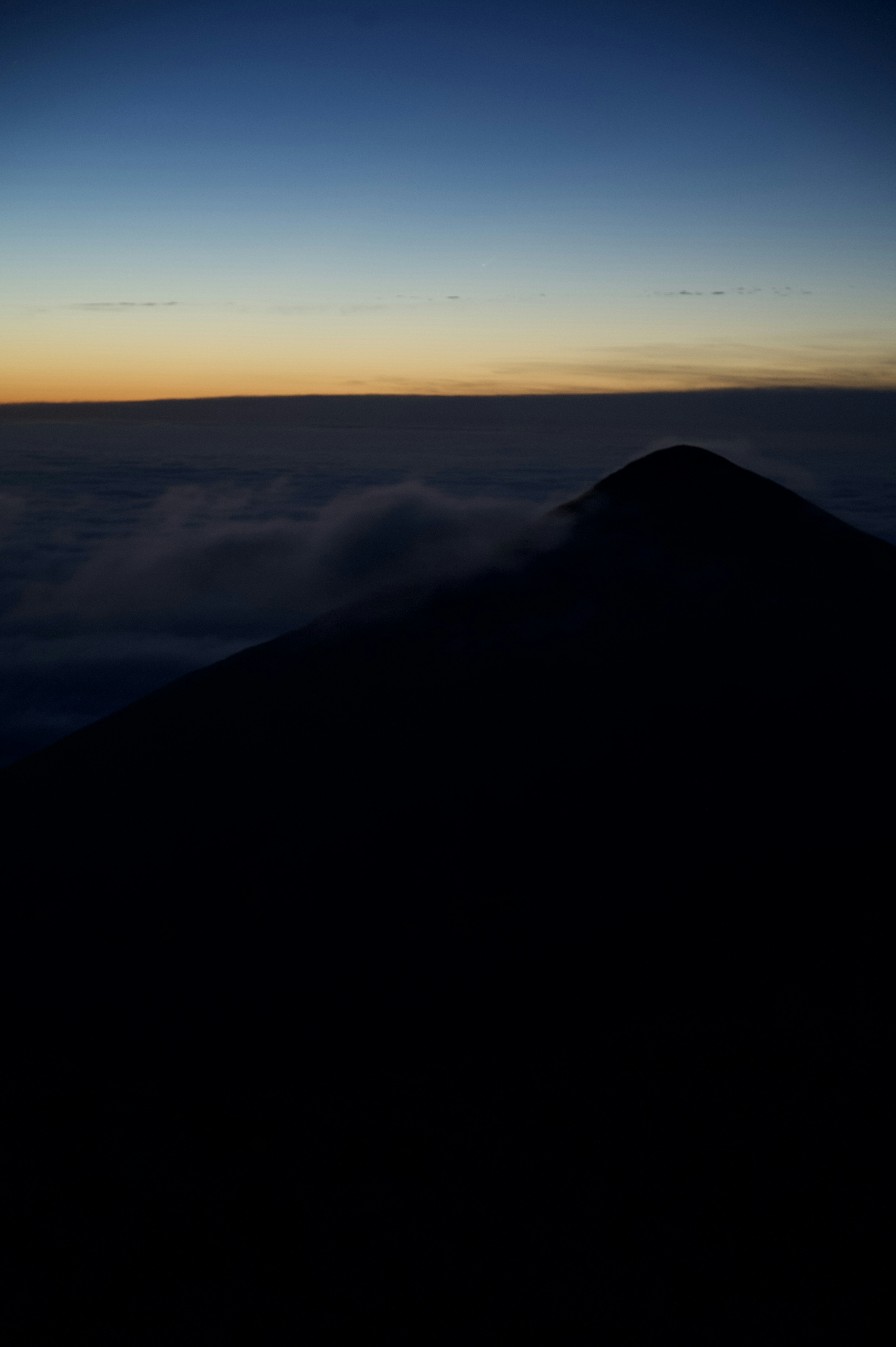 薄明かりの中の山と雲海のシルエット