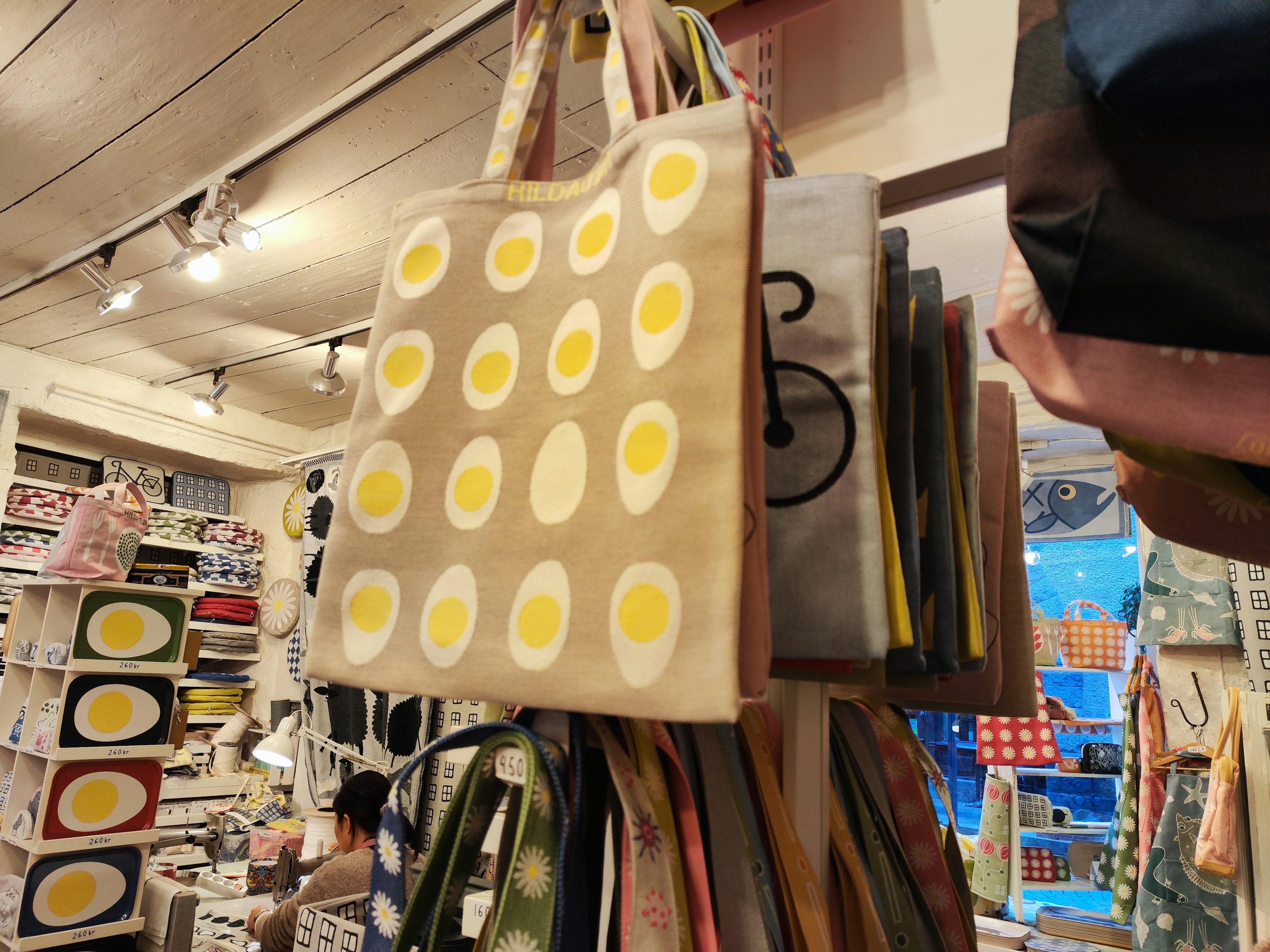 A tote bag with egg patterns hanging in a shop interior