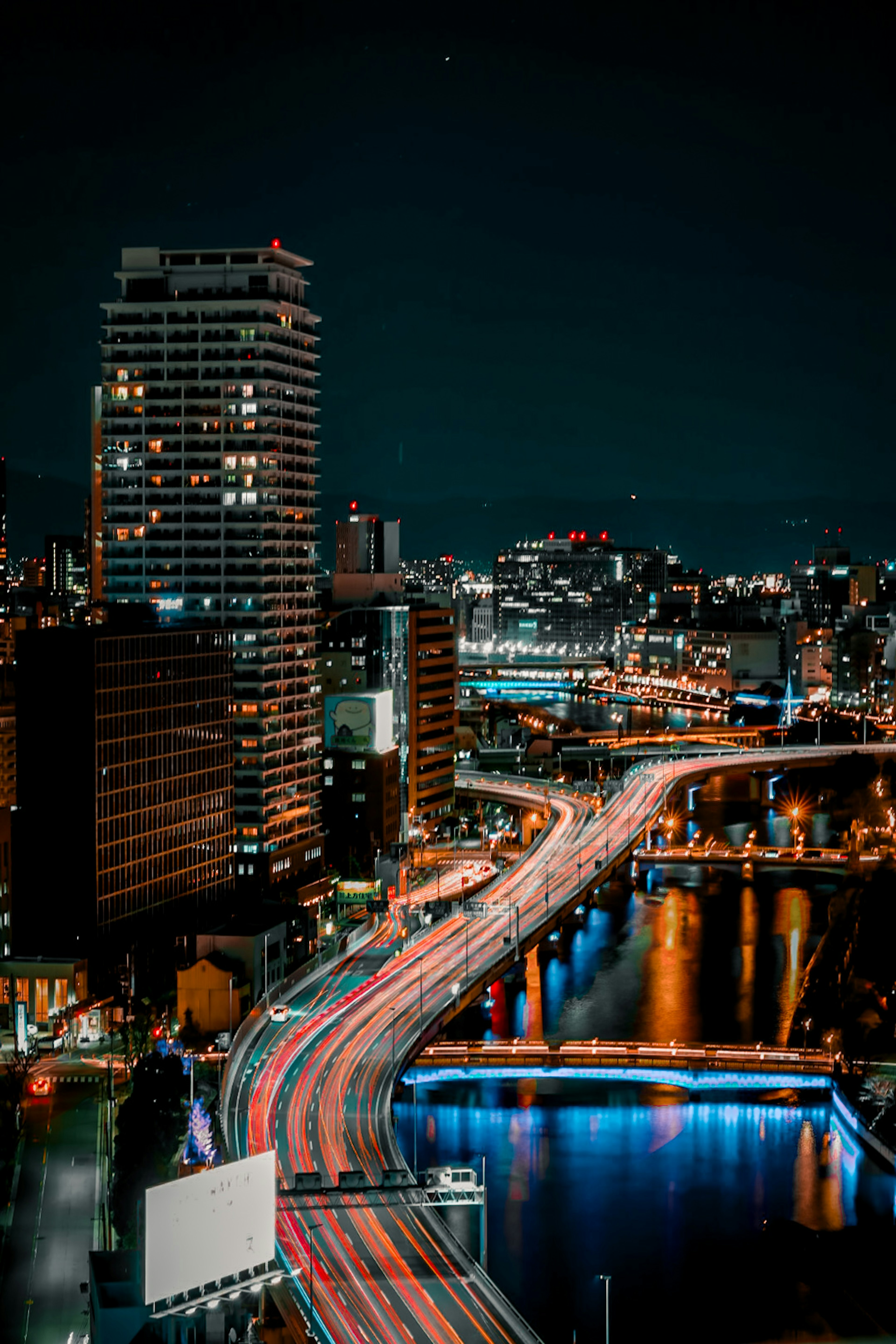 Cityscape at night with flowing car lights and skyscrapers