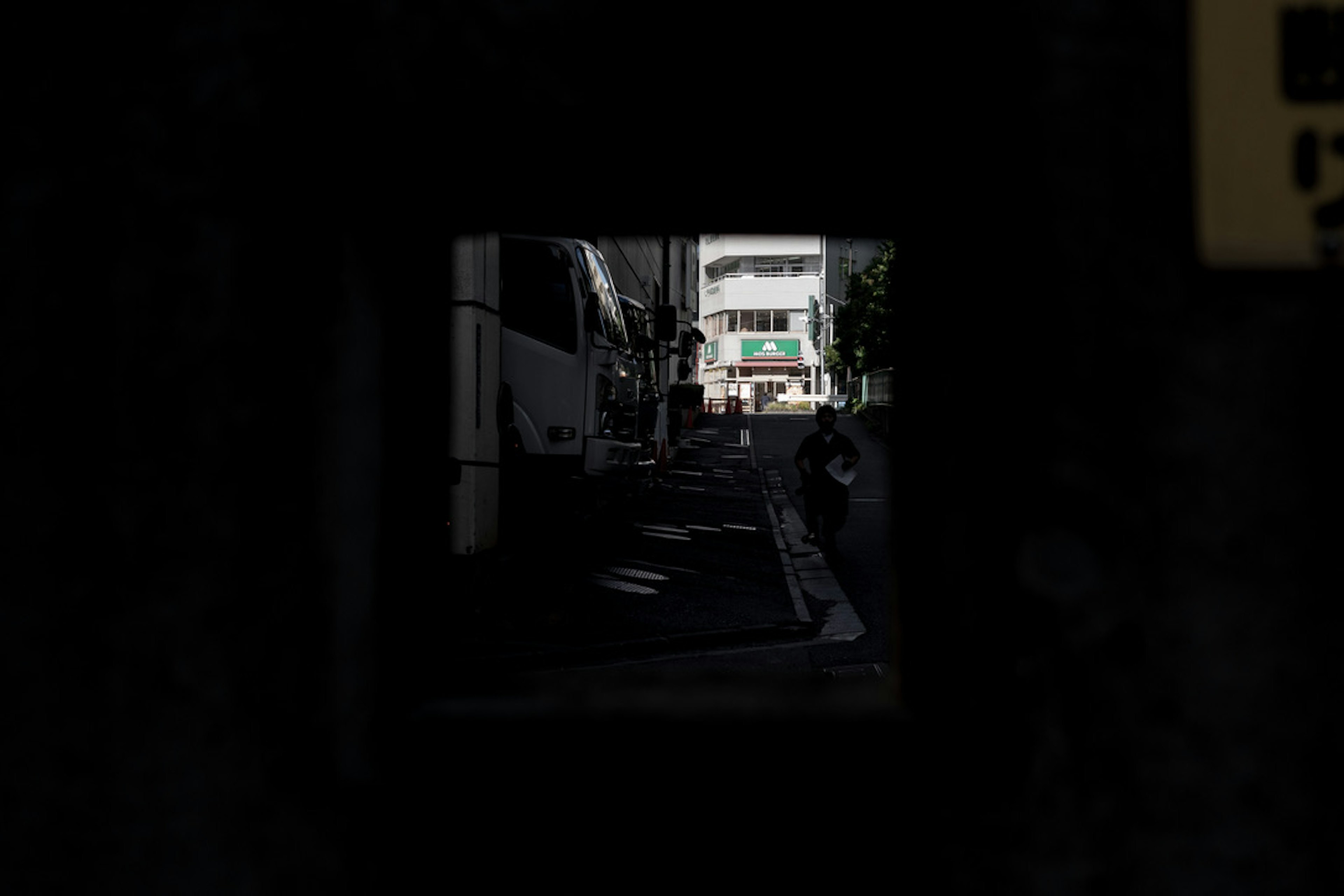 Bright street and buildings visible through a dark tunnel