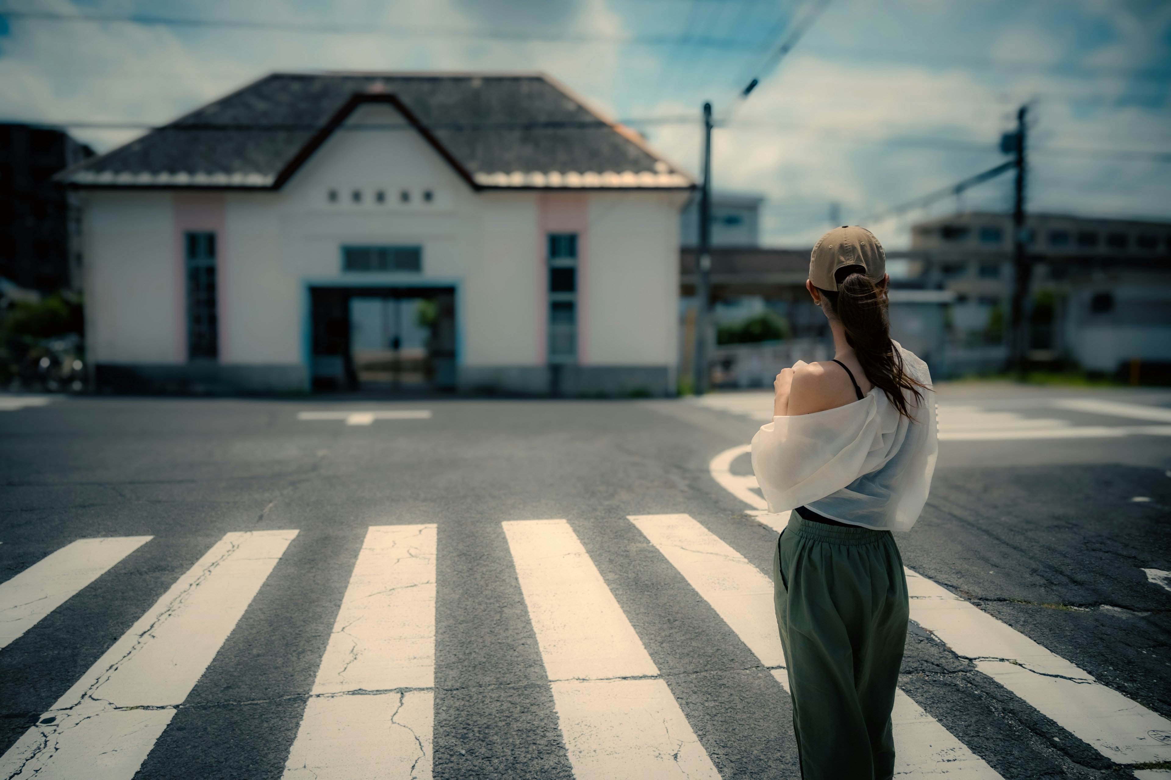 A woman standing at a crosswalk with a white building in the background