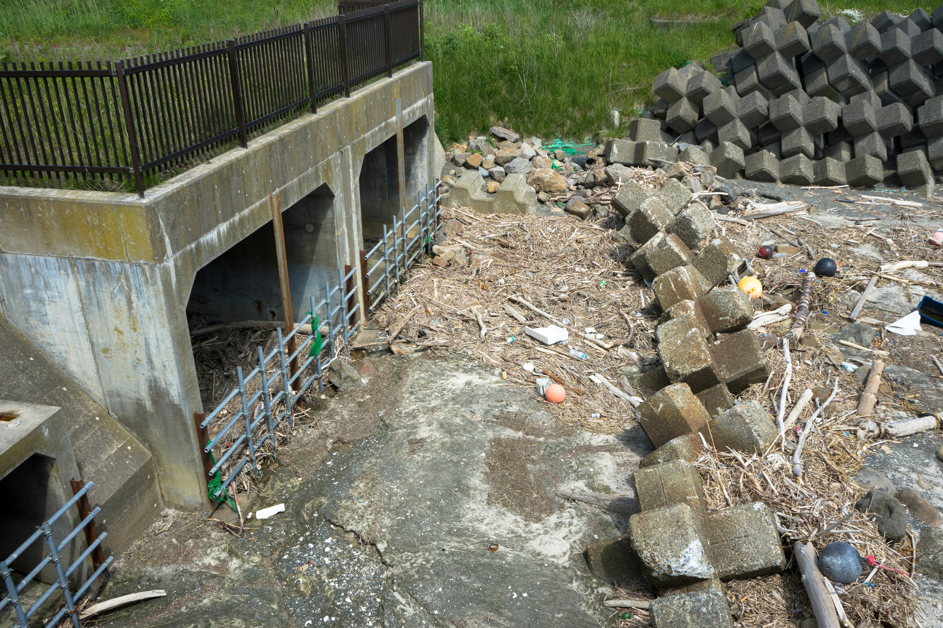 Szene mit Betonbauwerken in der Nähe eines Deichs und angesammelten Trümmern