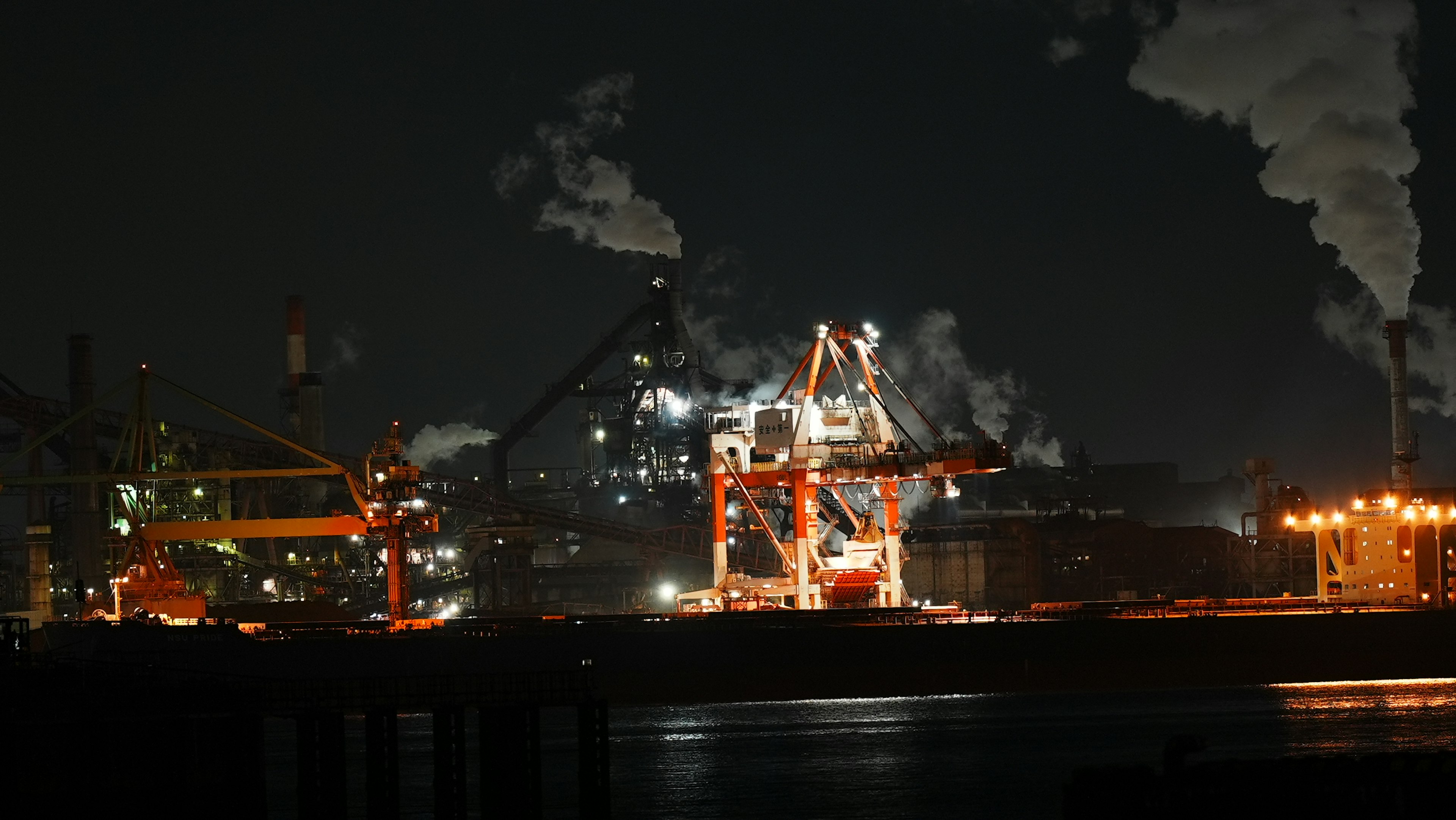 Nächtliche Ansicht von Industriekranen und Schornsteinen