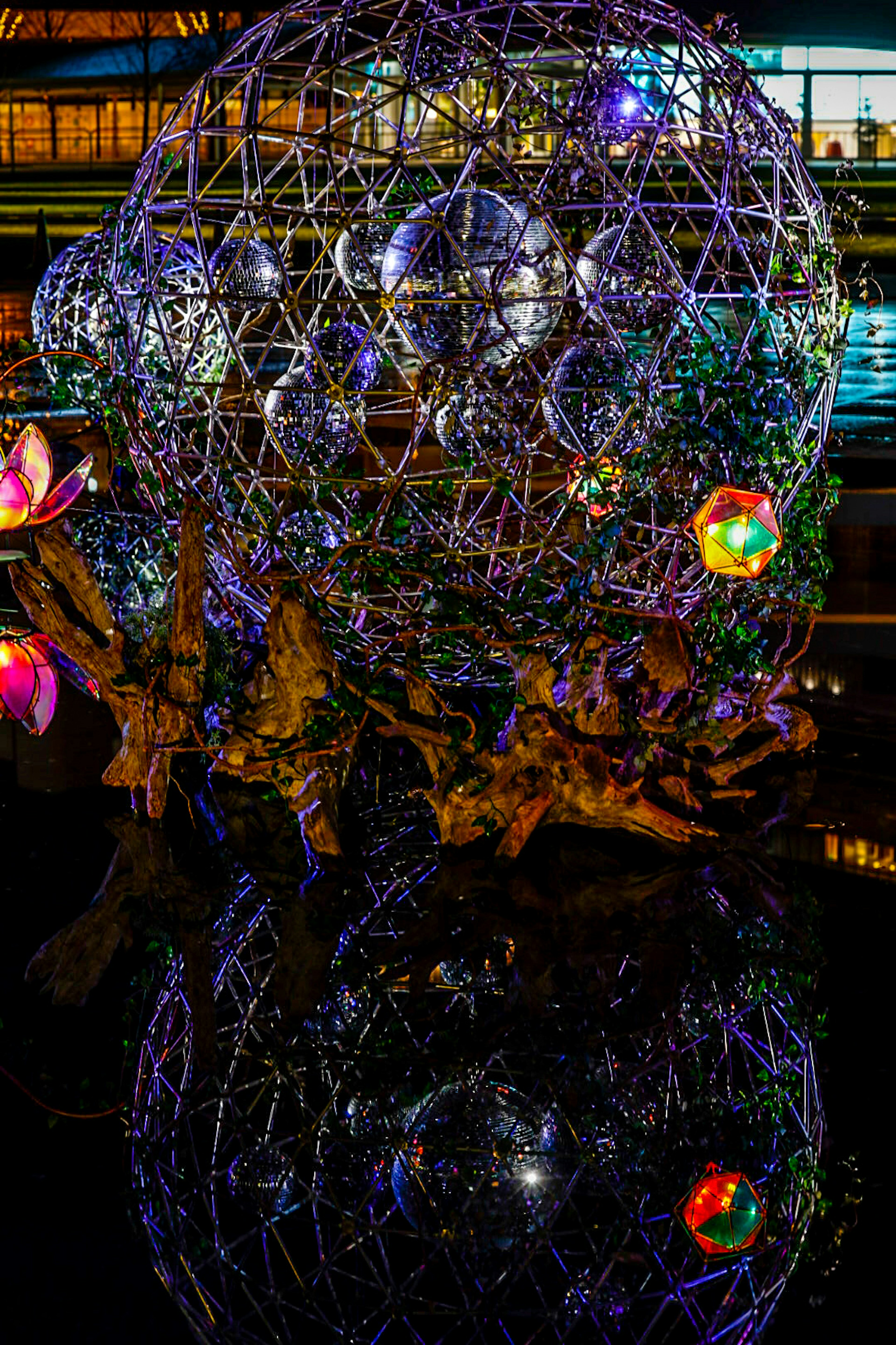 Sculpture sphérique illuminée dans un parc la nuit avec des reflets