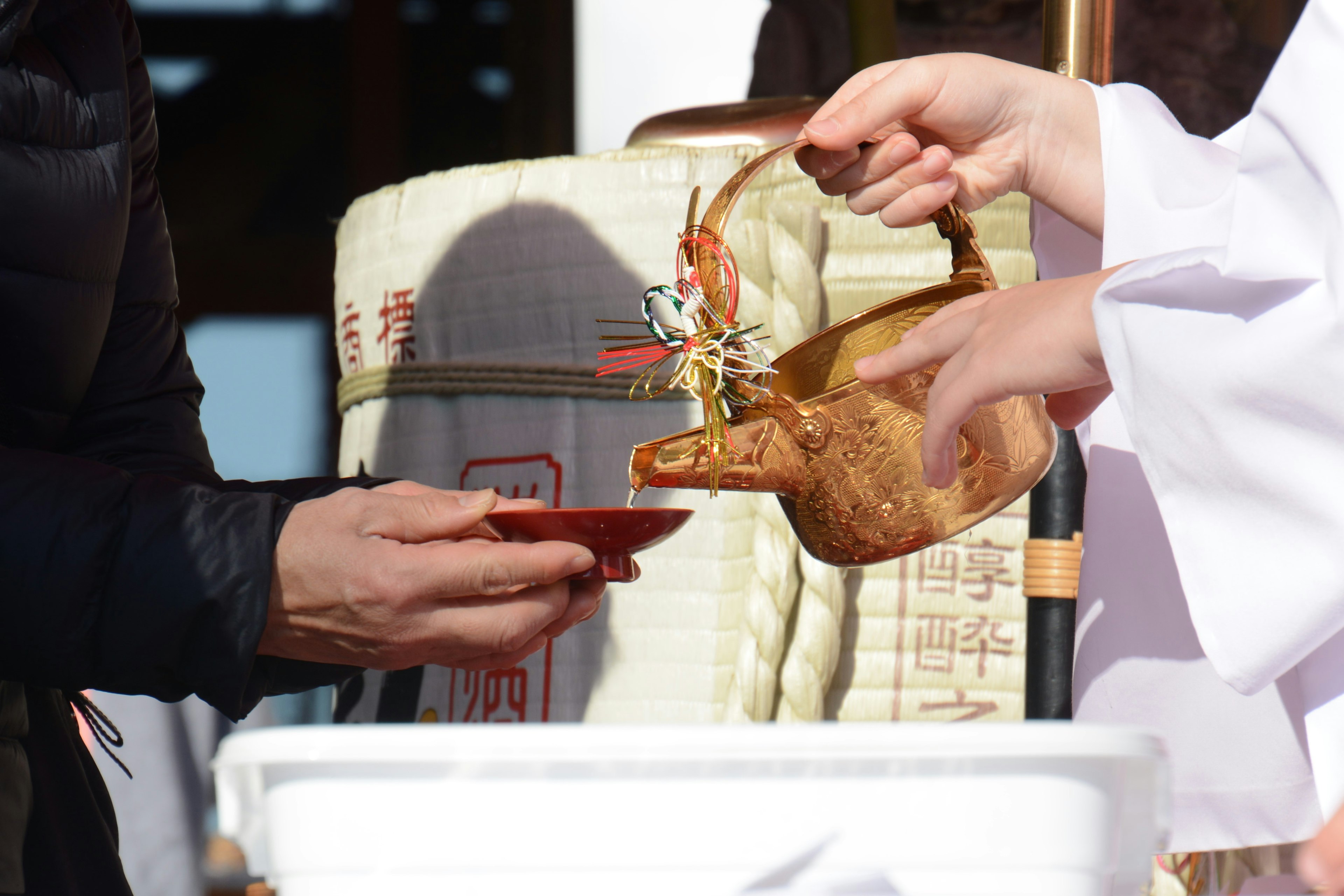 Seorang pendeta Shinto menuangkan sake ke dalam cangkir seremonial selama ritual