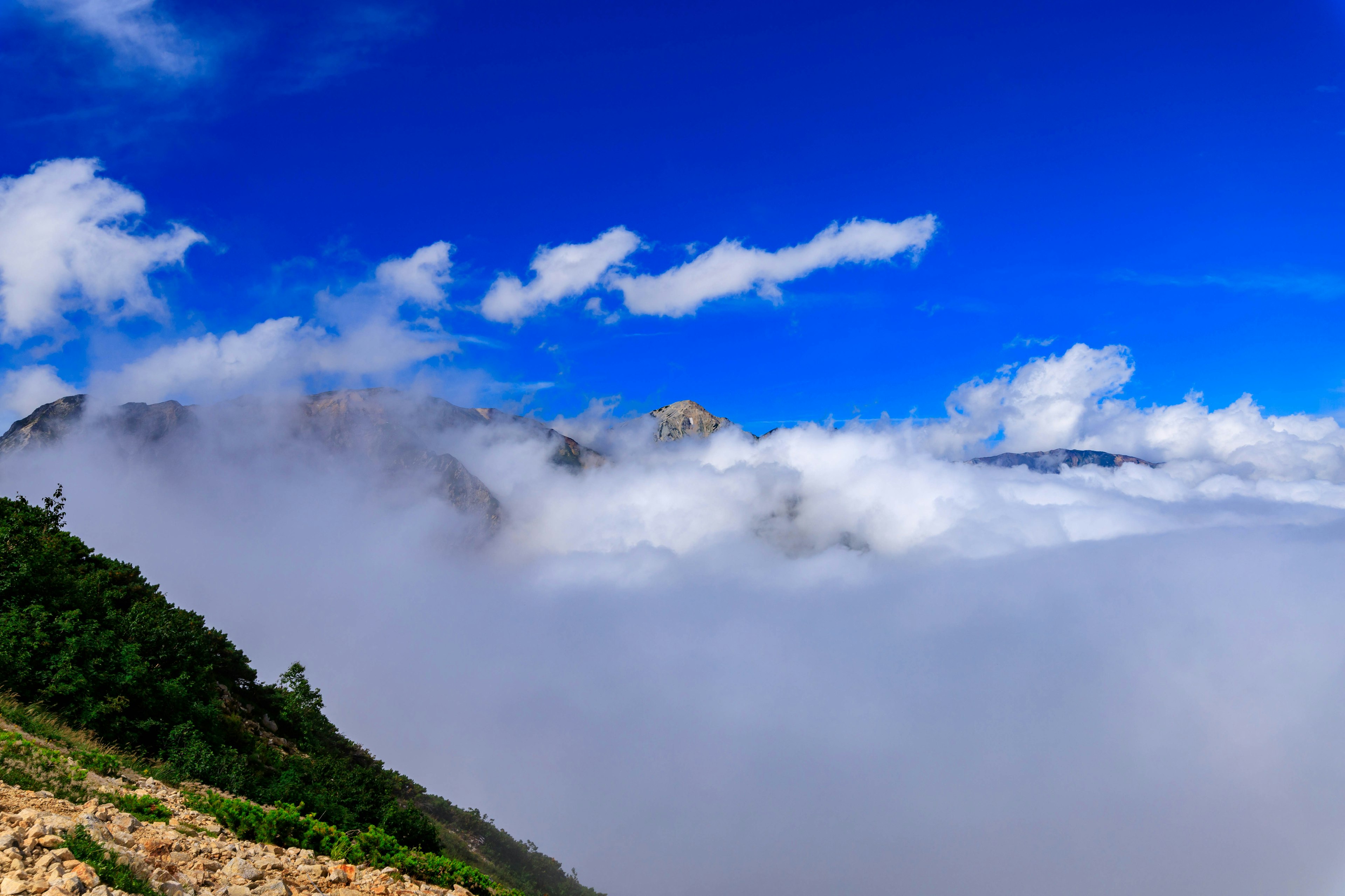 Vista escénica de montañas cubiertas de nubes bajo un cielo azul