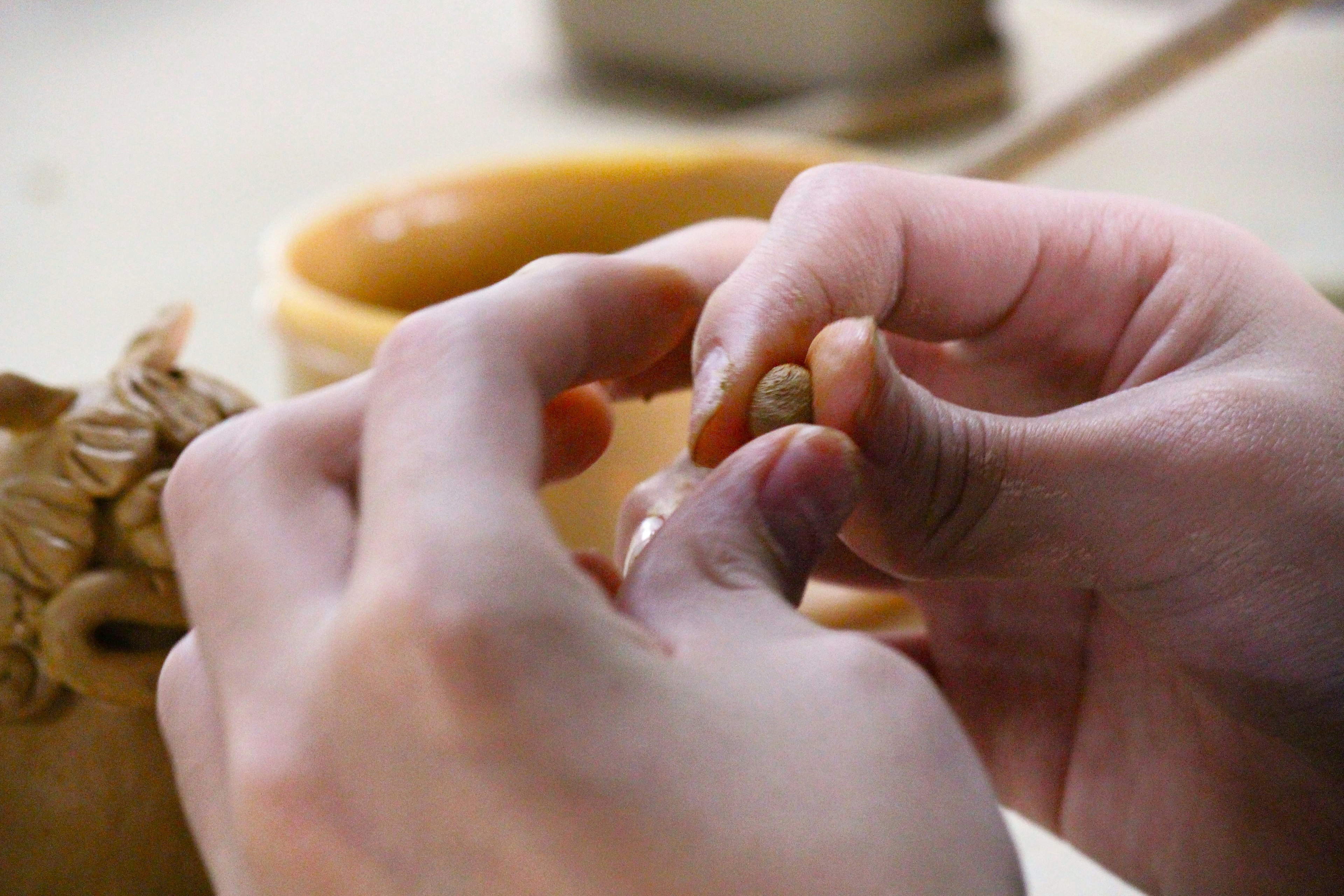 Hands shaping clay with focus on intricate details