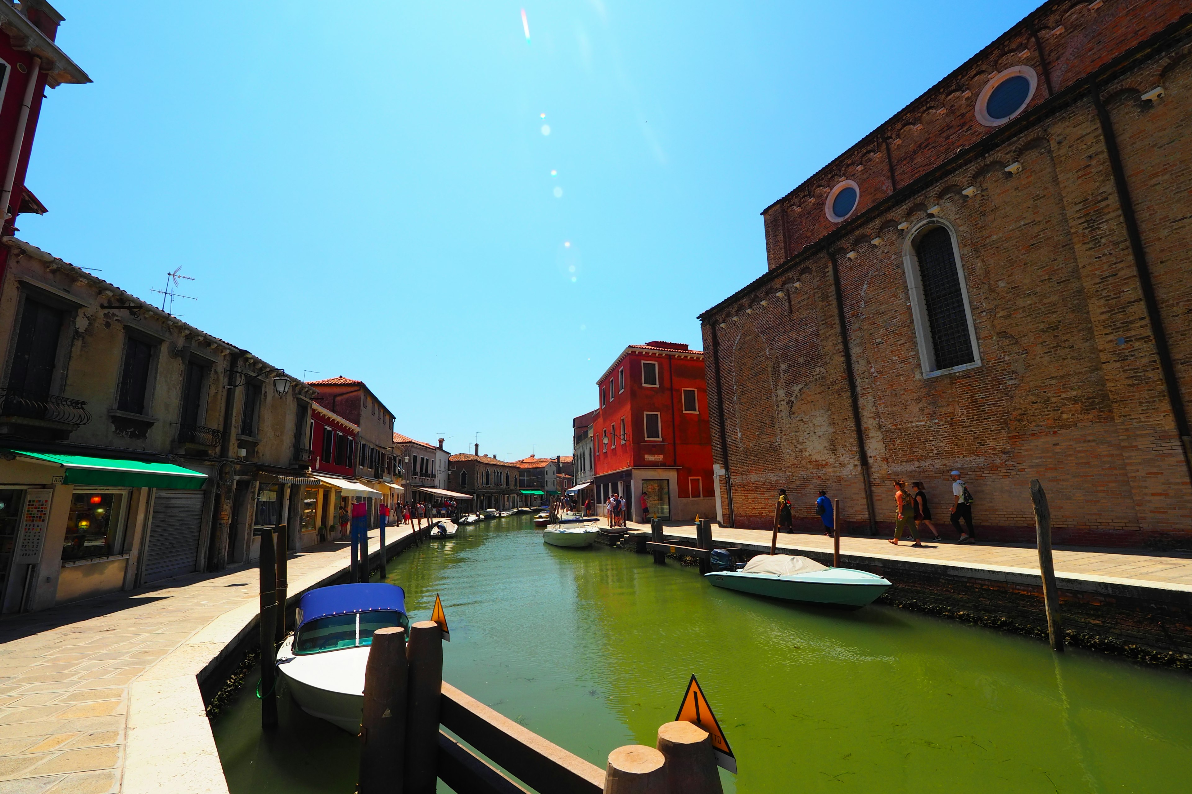 Bunte Häuser entlang eines grünen Kanals in einer venezianischen Landschaft