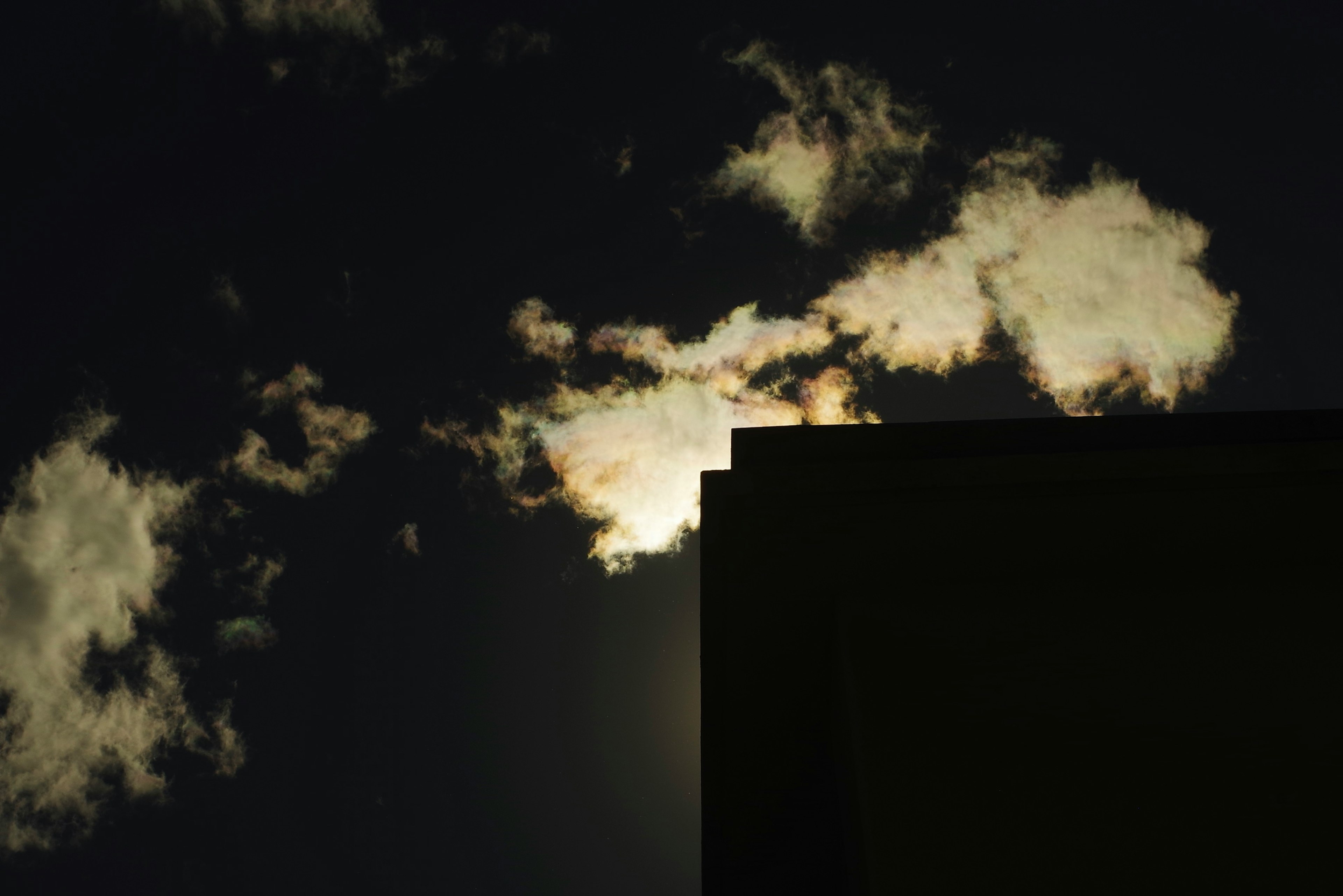 Silhouette bangunan di latar belakang langit gelap dengan awan putih